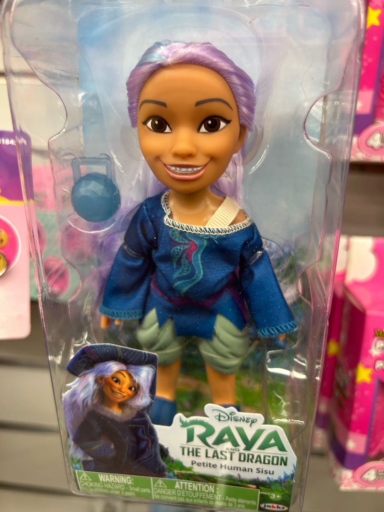 A doll of Raya from Disney’s Raya and the Last Dragon with a terrifying smile and uncanny eyes on the pegs at a dollar store.