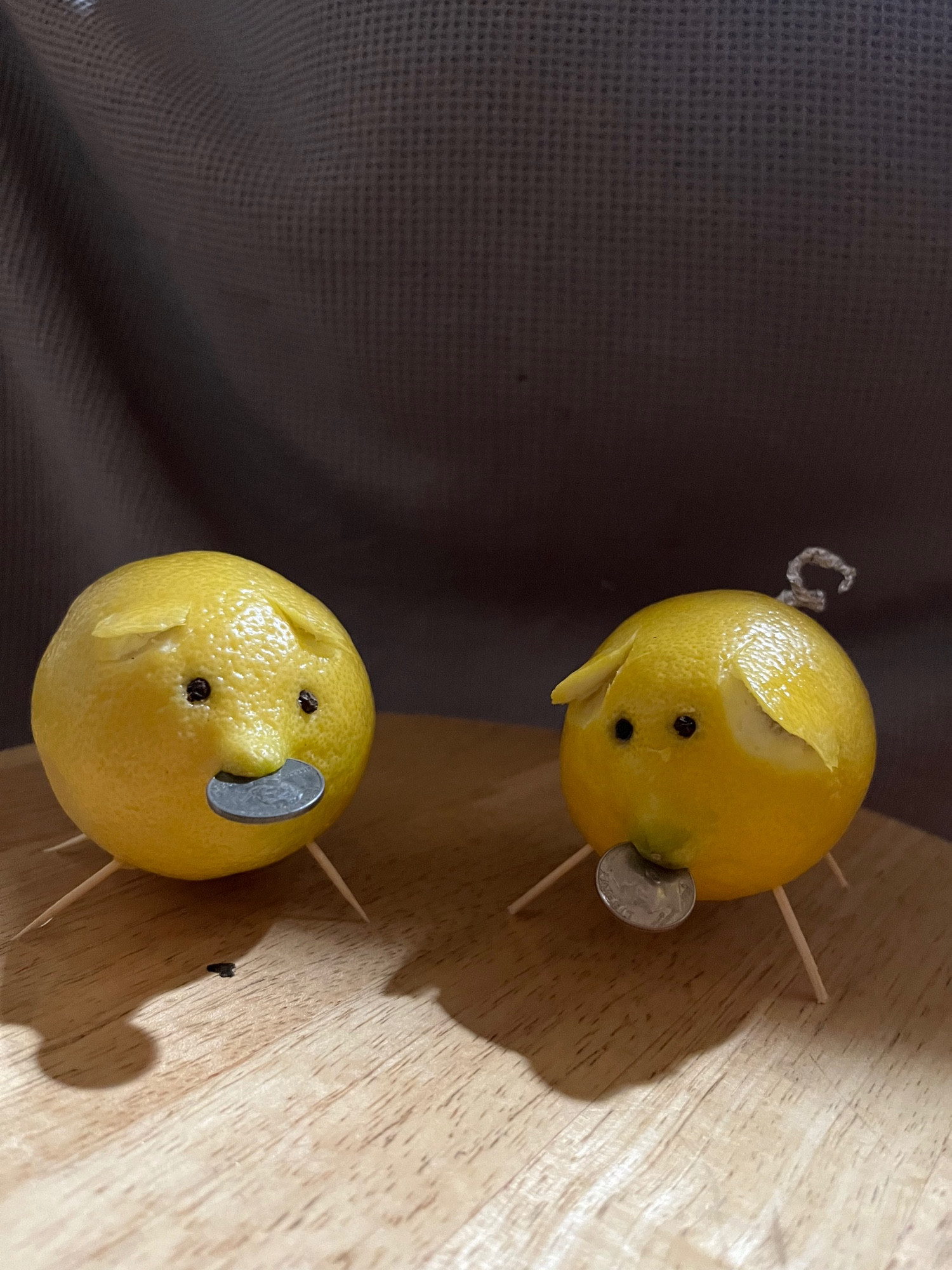 Lemon piglets with toothpick legs, peppercorn eyes, and shiny coins in their mouths.