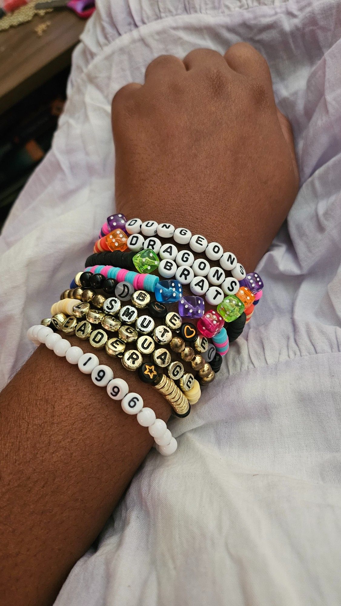 Arm covered with colorful friendship bracelets with various words and symbols