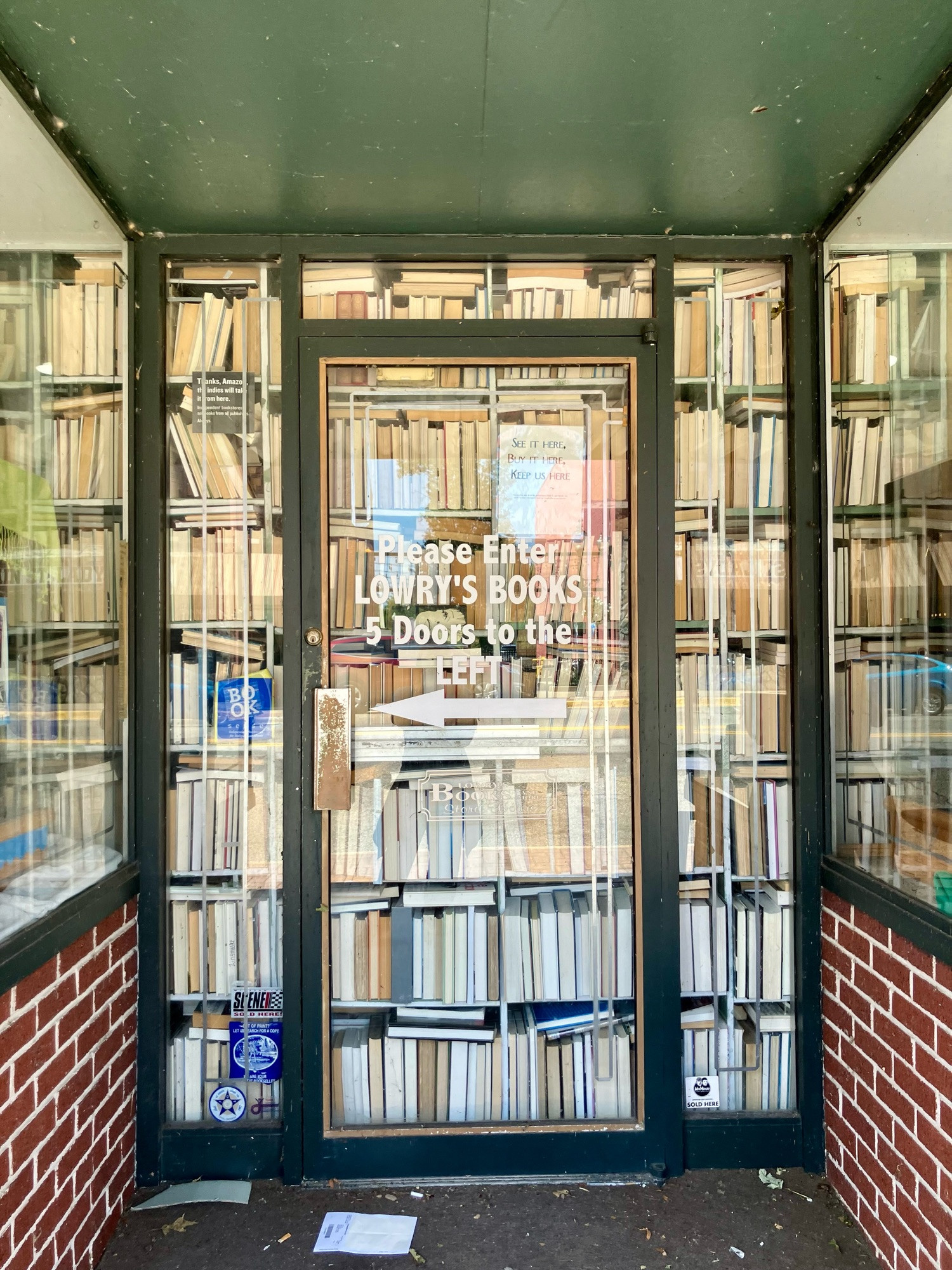 Exterior of Lowry’s Bookstore with floor to ceiling stacks of books seen through glass door and windows