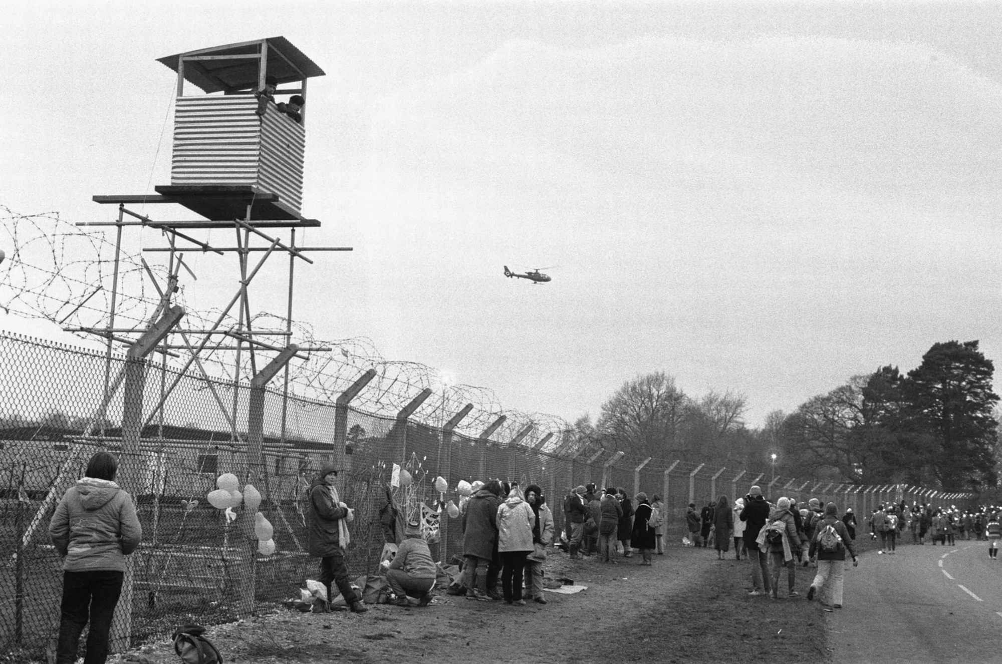 Some of the 50,000 women leaving the airbase perimeter are observed by soldiers in a sentry post tower as an army helicopter flew overhead. Photo and caption from Berkshire Live. 

https://www.getreading.co.uk/news/berkshire-history/gallery/powerful-1983-greenham-common-protest-22193828