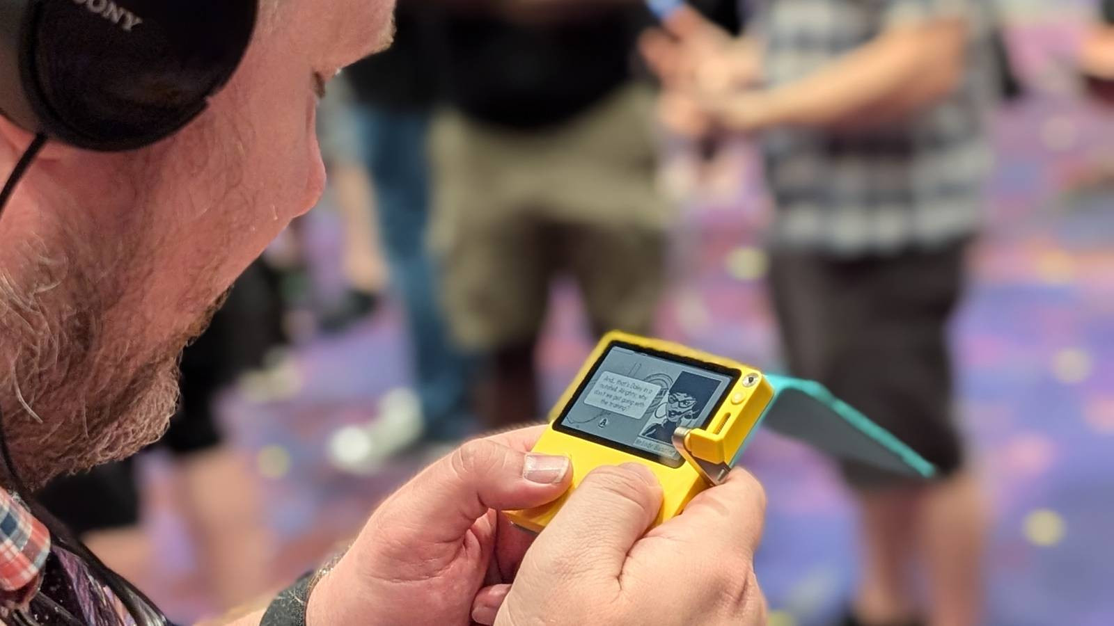 A dapper gentleman tries out Agents of Groove on a Playdate console at PAX West 2024