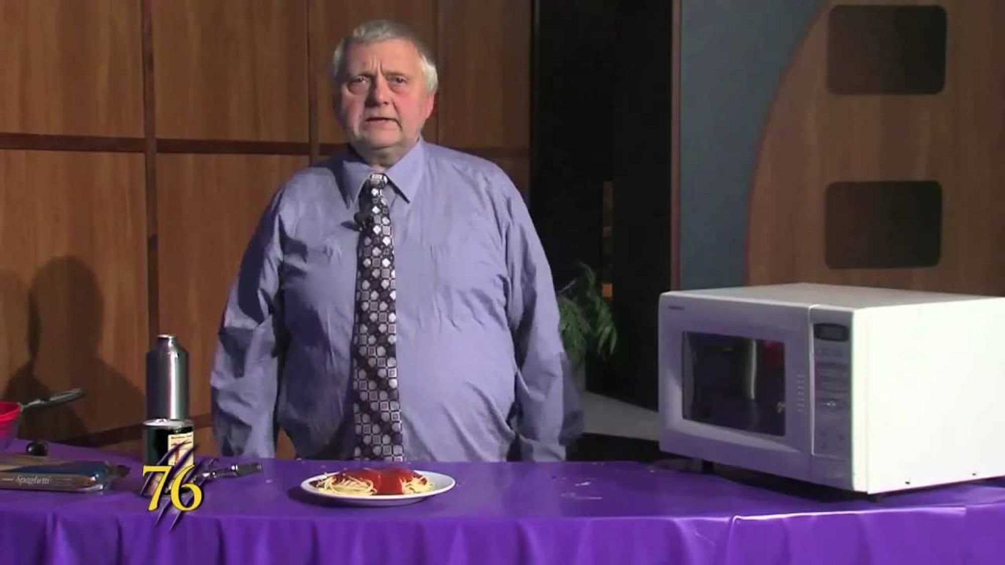 A still image from the Weber Cooks videos, featuring the miserable cook standing in front of a miserable plate of spaghetti