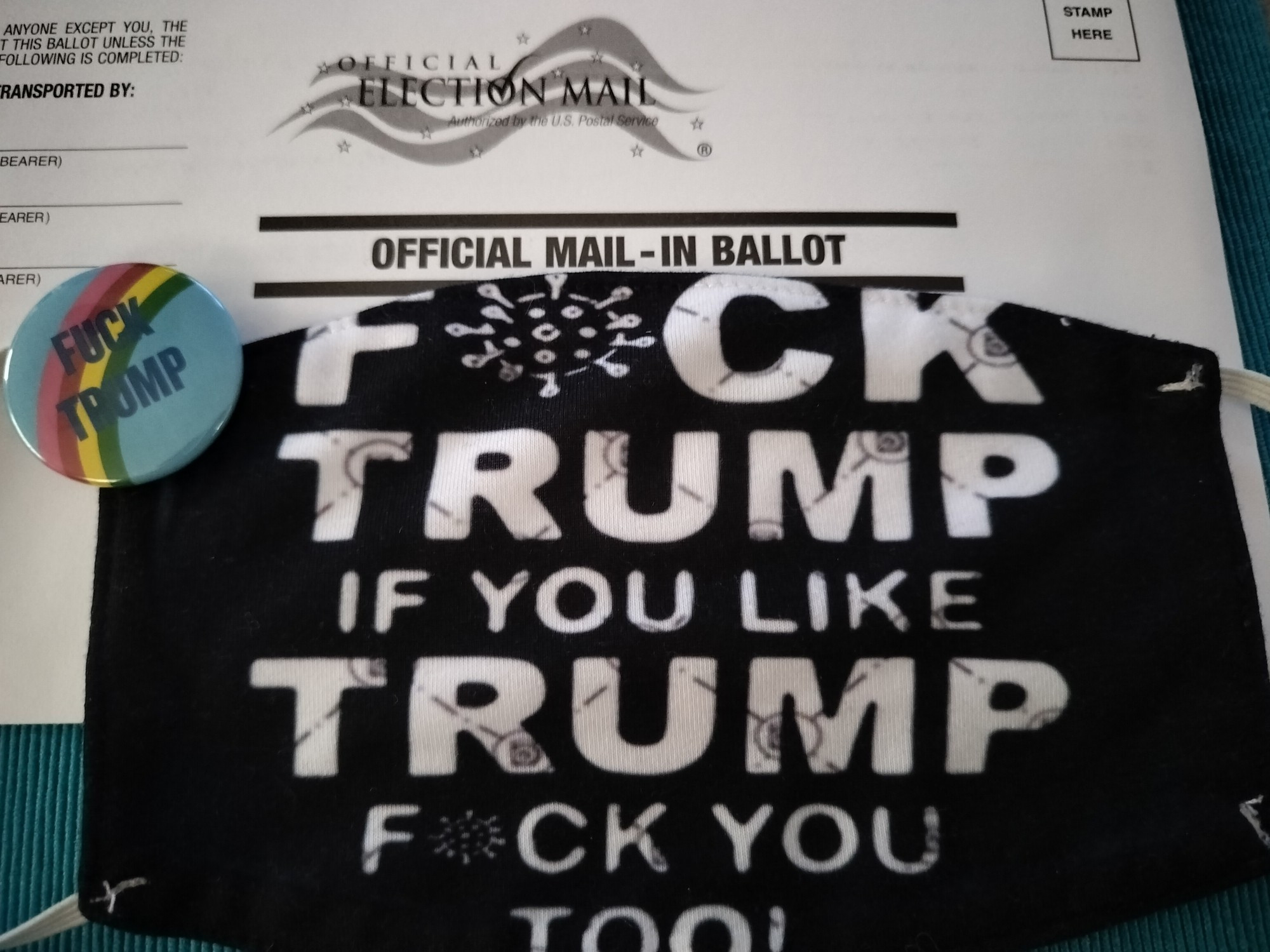 Picture of a 2024 General Election mail in ballot with a mask that reads "F*ck tRump If you like tRump f*ck you too" and a blue badge that reads "Fuck tRump" with a rainbow through the text