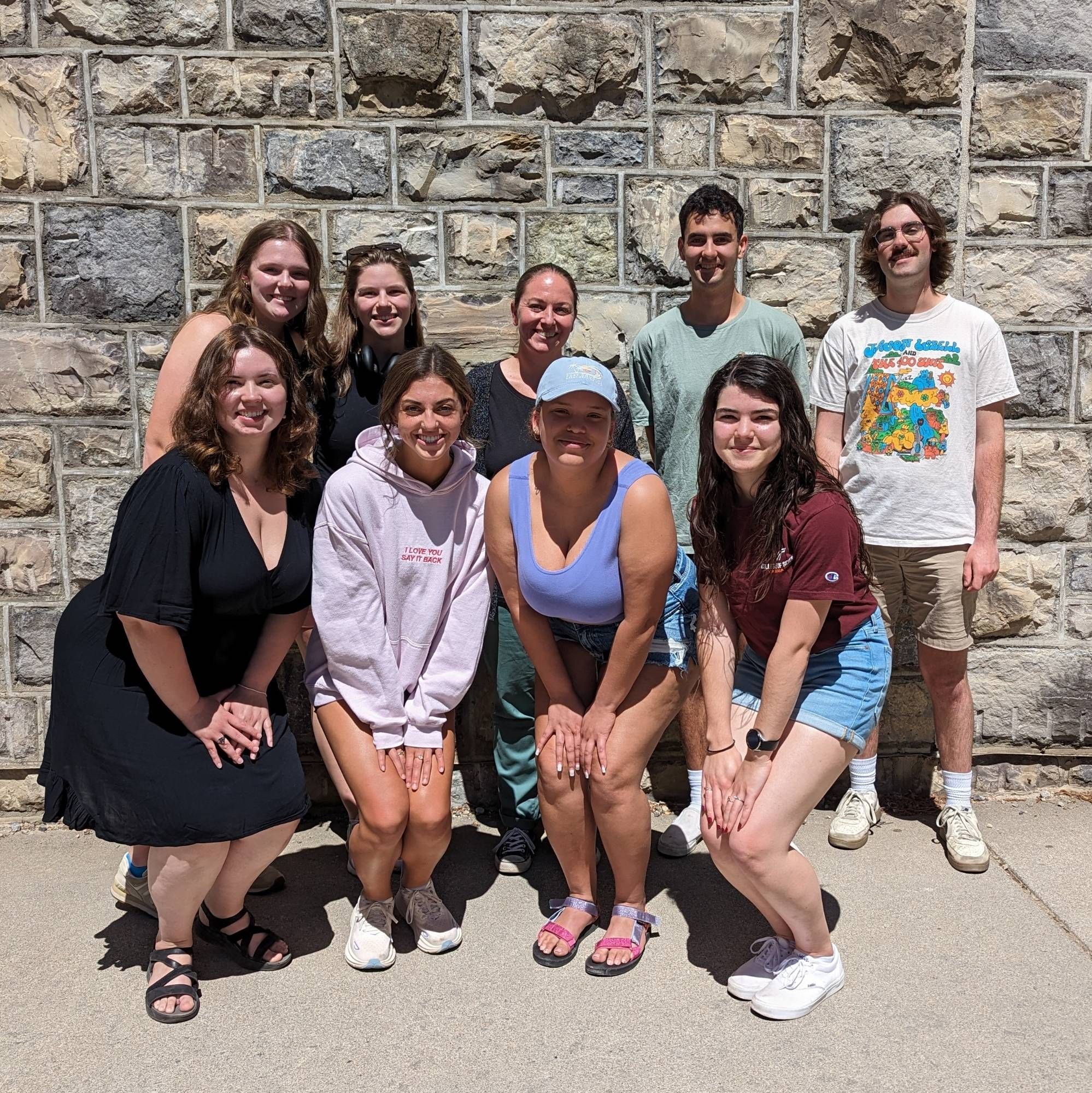 Eight scientists standing outside for a picture in front of a stone wall