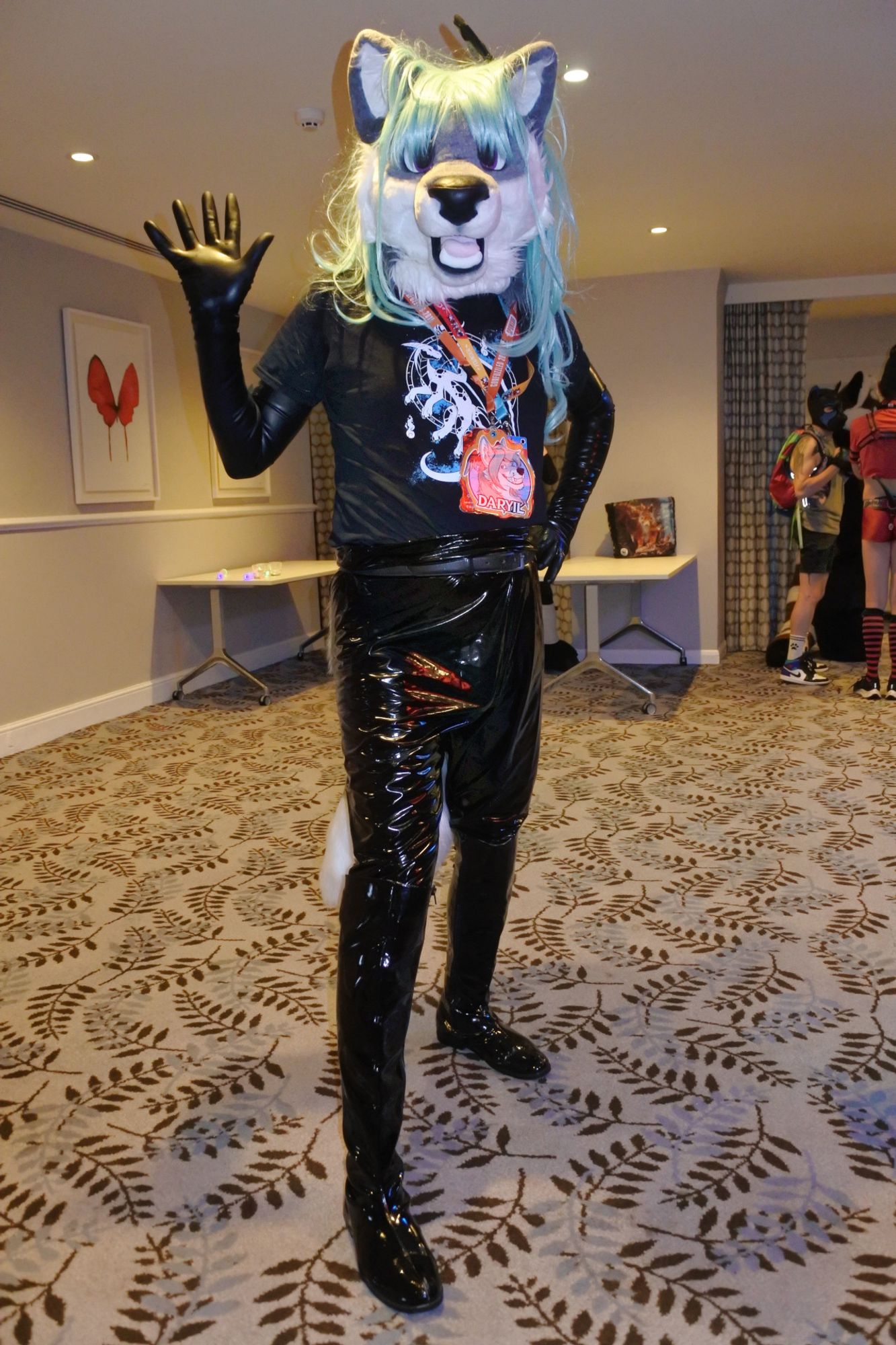 Fursuit photo - Daryil the fox incubus waving to the photographer at Pawsome.  He is wearing latex opera gloves, a black T-shirt, stretch PVC leggings and PVC boots.

Photo taken by Mutley