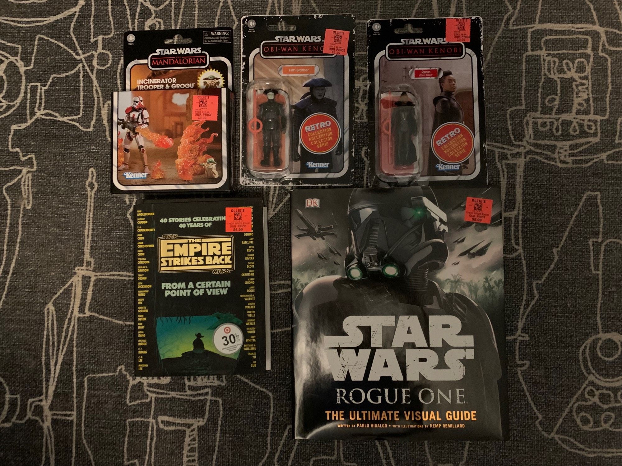 Five items from an Ollie's Discount Store. Top row are Star Wars action figures from the Mandalorian & Obi-Wan TV shows. Bottom row are two Star Wars books