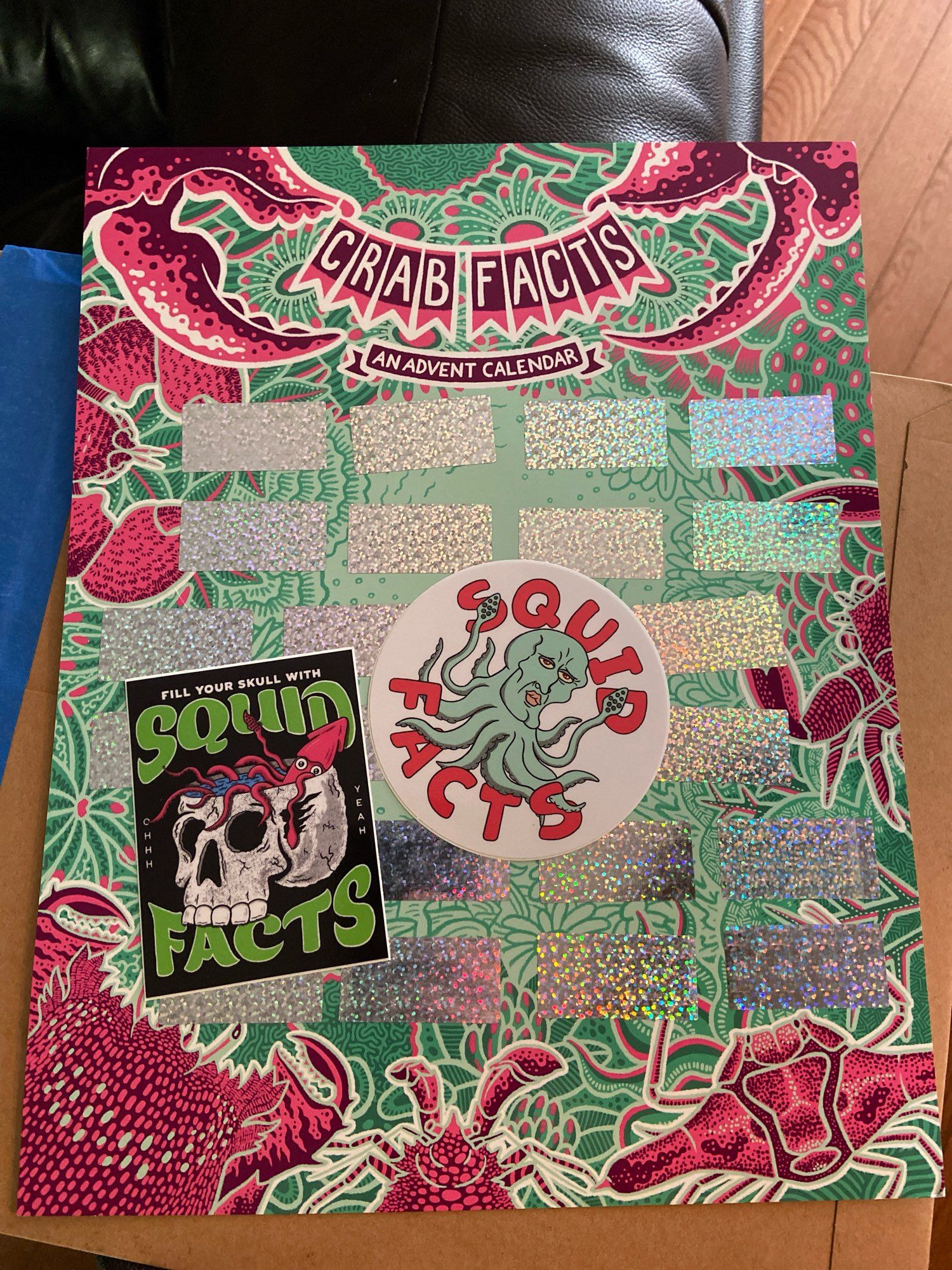 Image of a bright green, pink, and silver calendar and two squid facts stickers. One has a squid floating around in a human skull, the other is the stuff of nightmares.