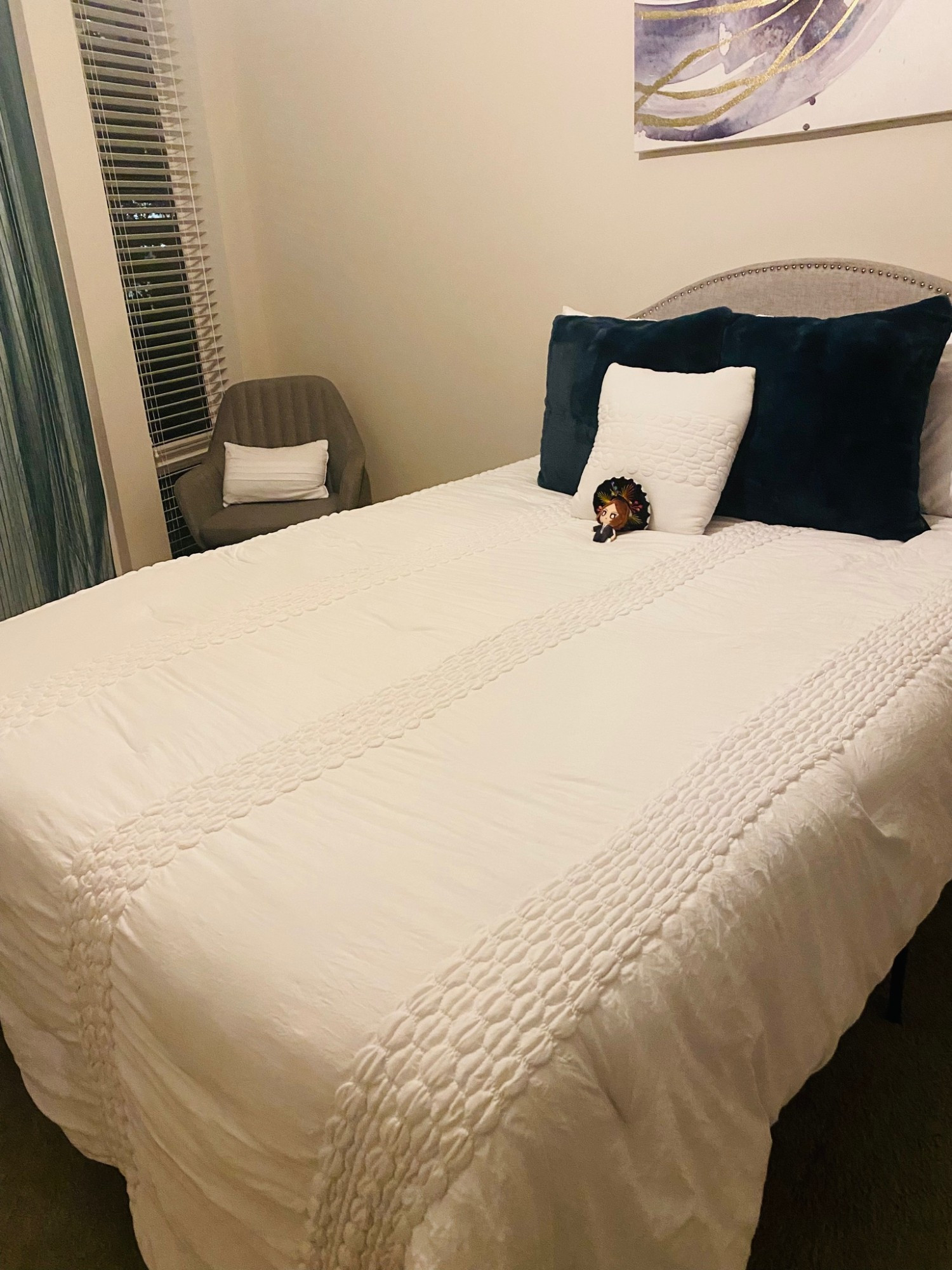 A tiny Tatsuya plush wearing a sombrero laying in a massive bed. A single tiny pillow supports him.