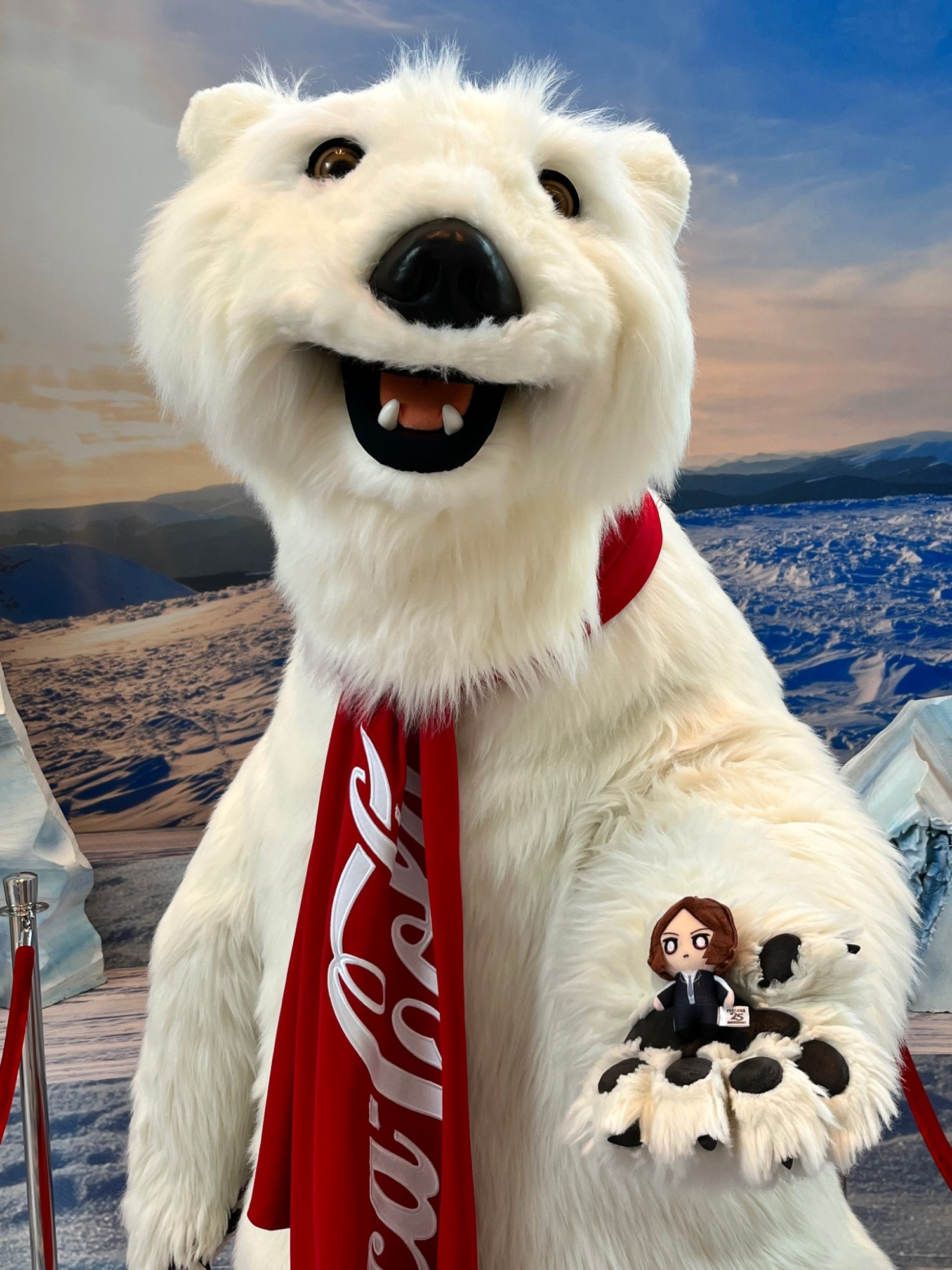 Tiny Tatsuya plush being held in the hands of a guy in a giant animatronic Coca Cola polar bear suit. The bear is smiling happily and content while Tatsuya looks nervous. The bear's handlers were so happy to see Tatsuya being held