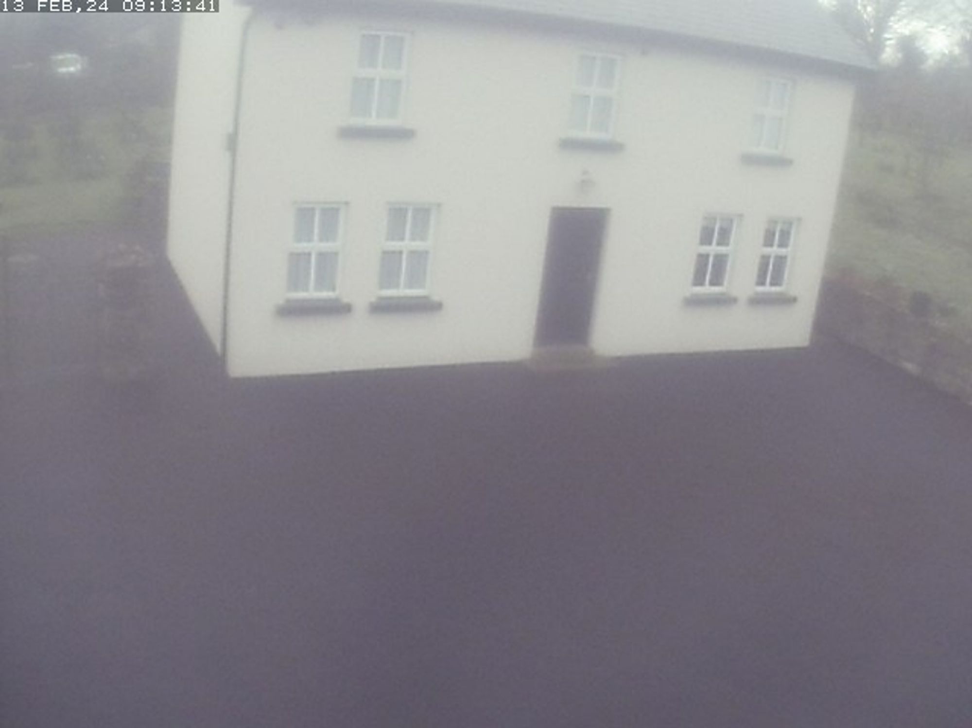 cctv picture of a white house in fog. all the lines are weirdly straight, like it's 3d rendered with a low poly model