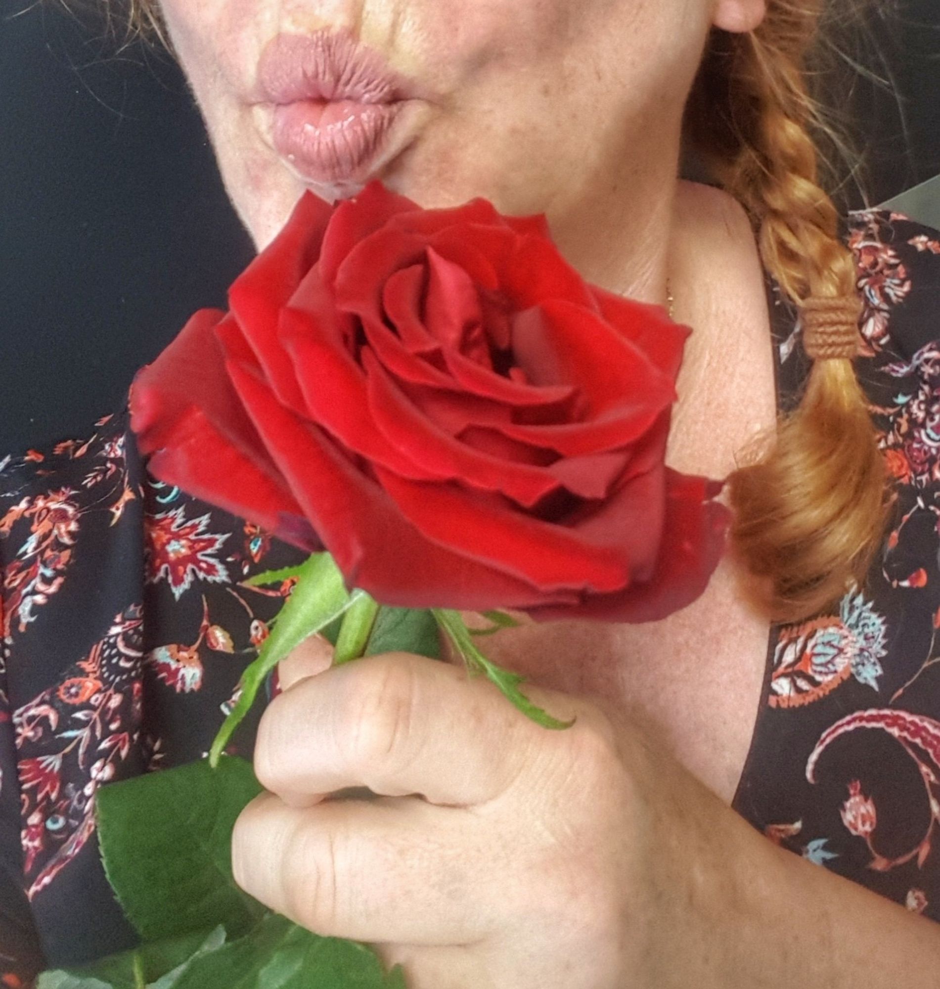 Selfie mit Kussmund und roter Rose in der Hand