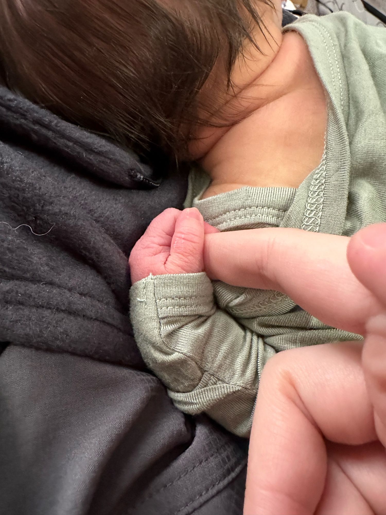 my newborn nephew holding onto my finger while he sleeps