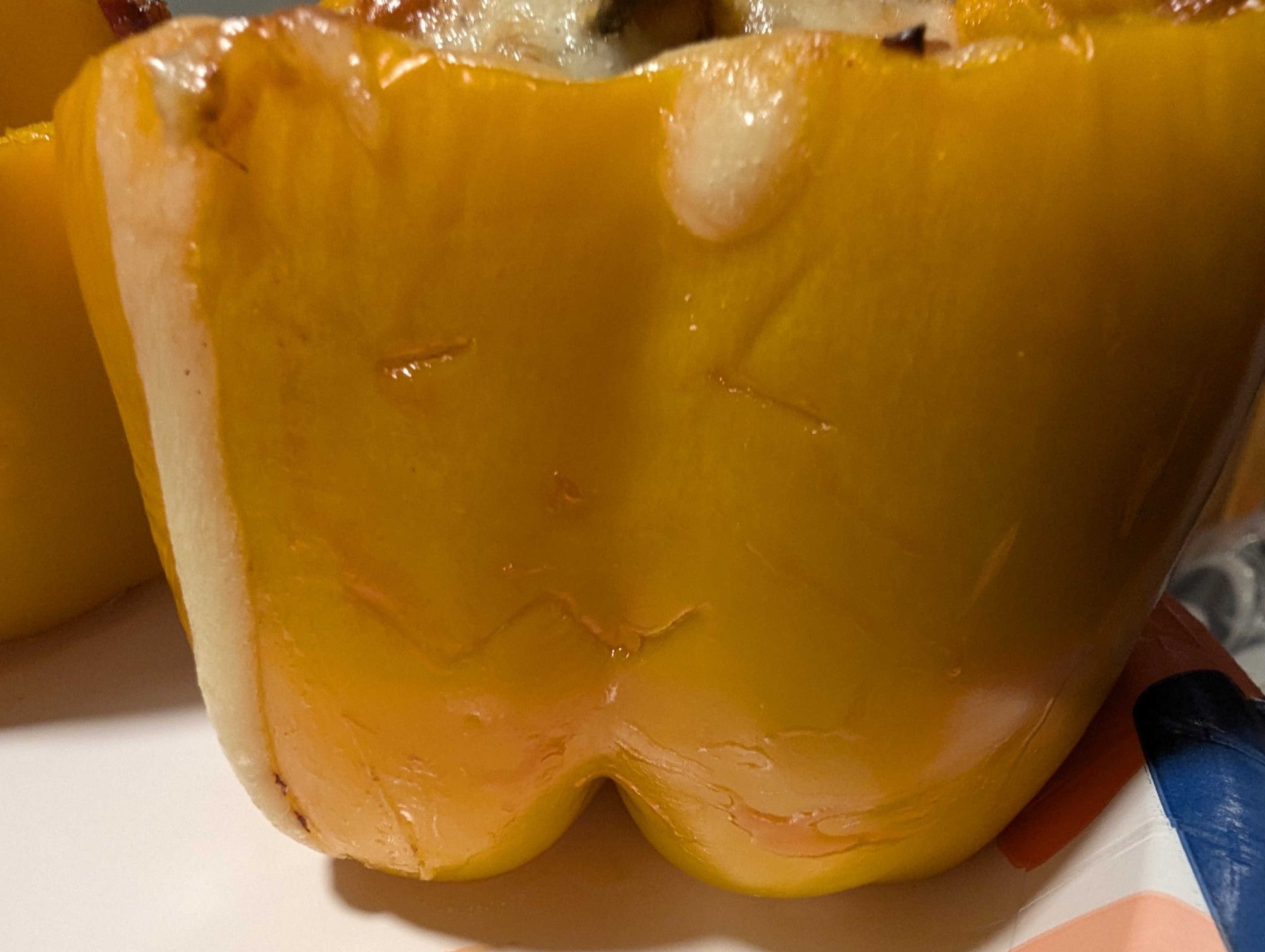 A yellow bellpepper sitting on a plate.

The top of it has been slice off and stuffed with a mix of chicken, cheese, and bacon.

It's also been cut into to give it a cute cat face