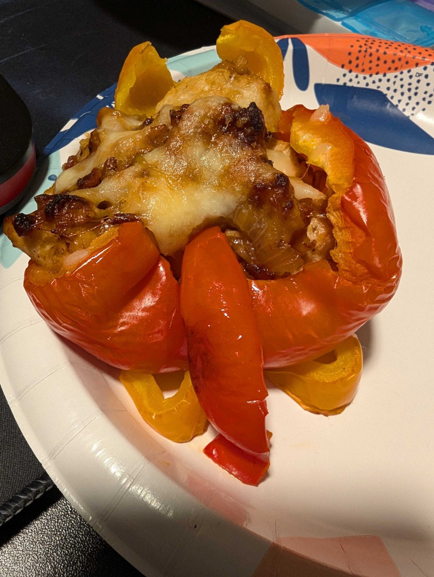 A red bell pepper with yellow bell peppers littered around it for decoration.

It's been cut in half and stuffed with a mix of chicken, cheese, and bacon.

It has cat ears, paws (front and back), and a tail, made out of cut up bits of bell pepper.

Can see my pill container in the background behind the plate.