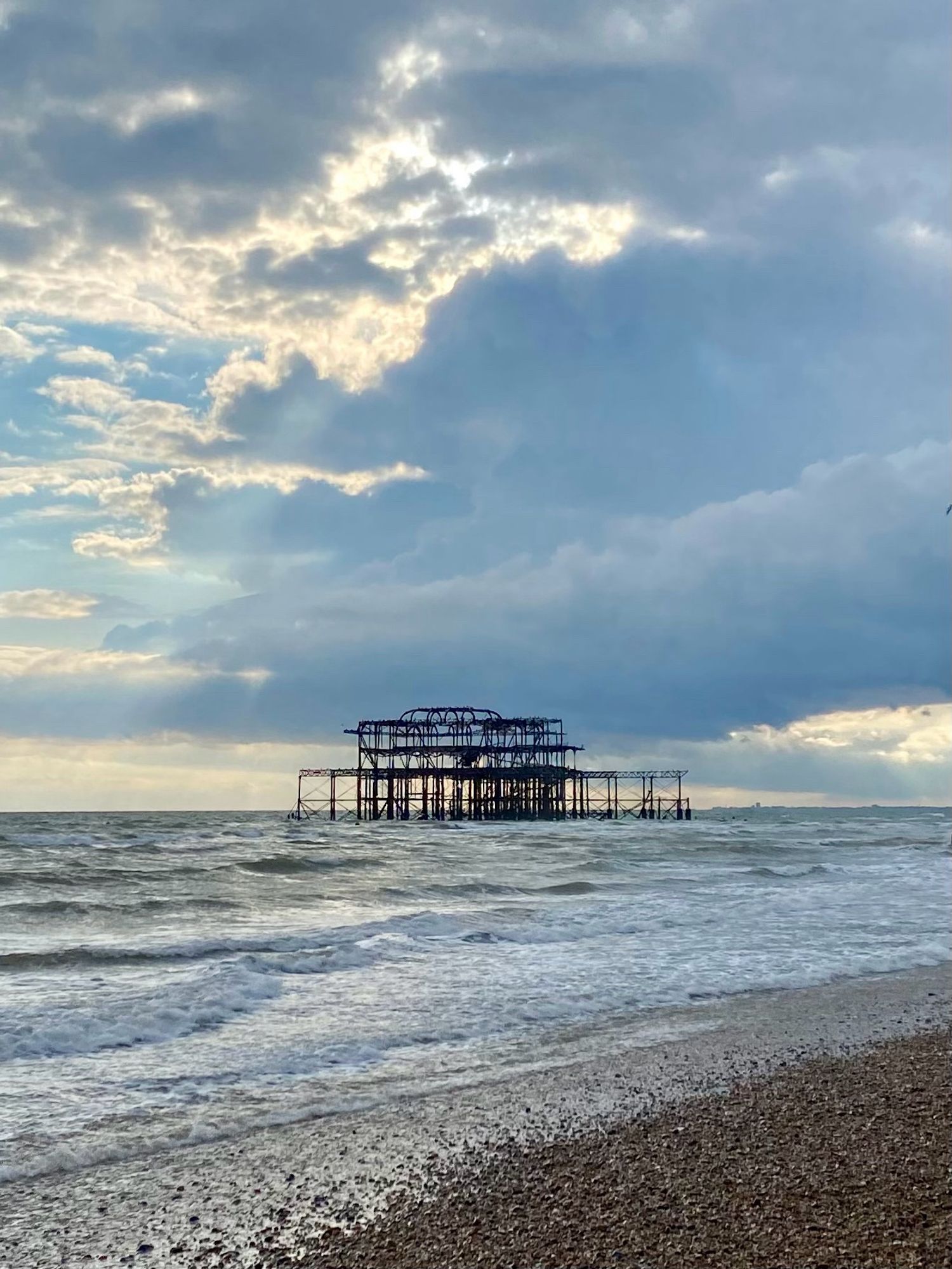 A derelict pier out at sea beside a beach