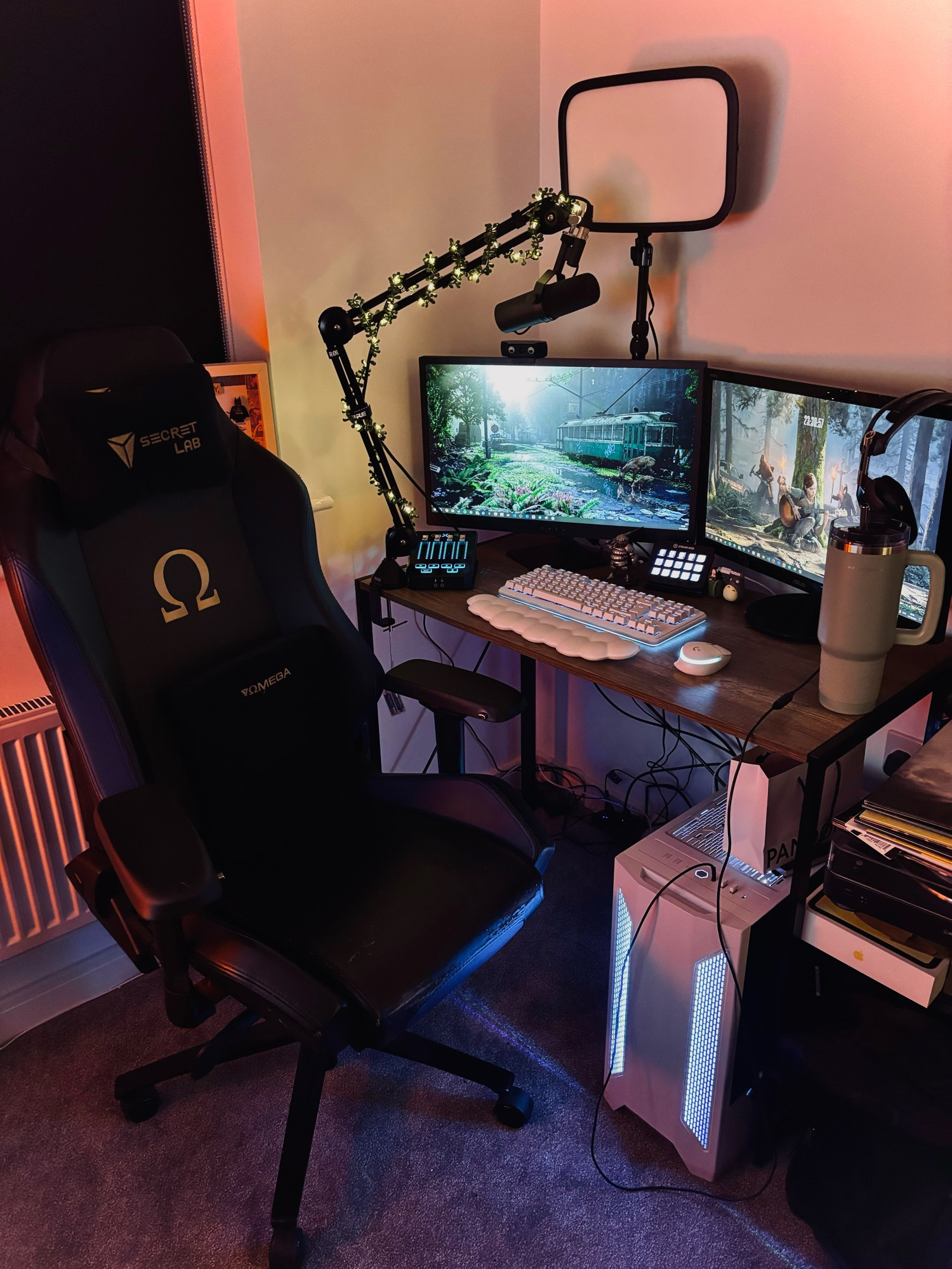 a small wooden desk with a computer on it, with two monitors, a white keyboard and mouse, a steam deck, goxlr and a secret lab black and blue chair 