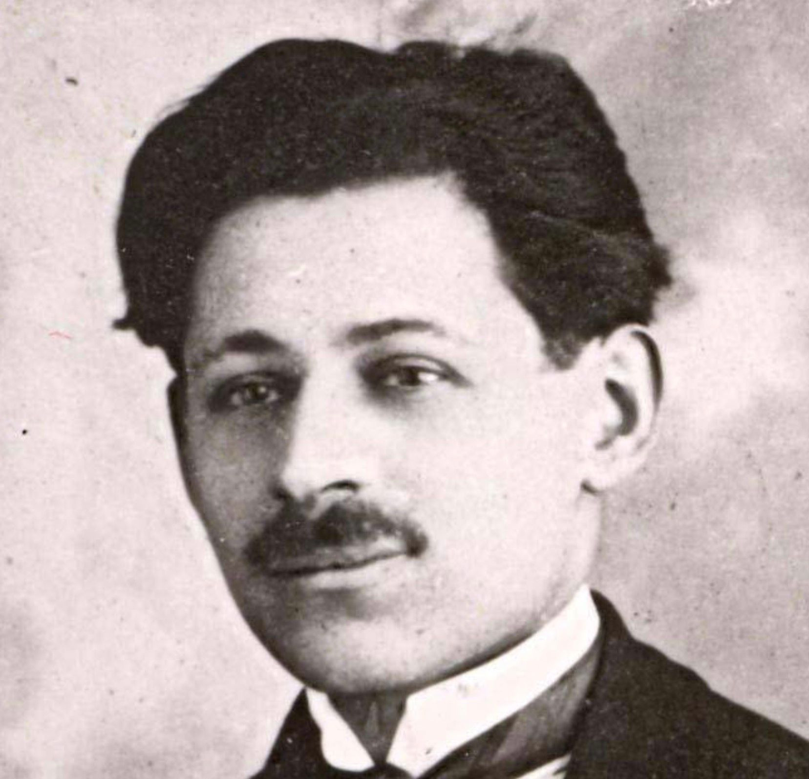 Black and white historical photograph of a man in a suit with a mustache and hair combed to the back.