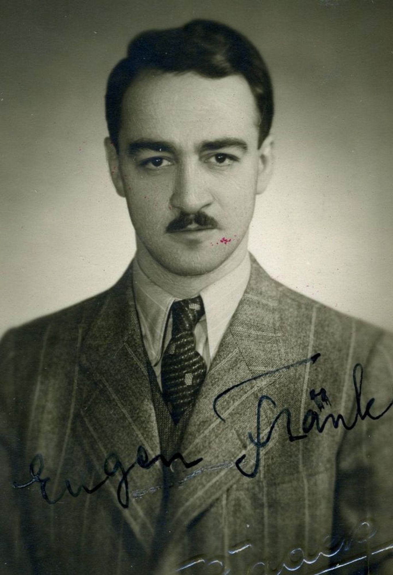 Vintage black and white portrait of a man in a suit and tie with a well-groomed mustache.