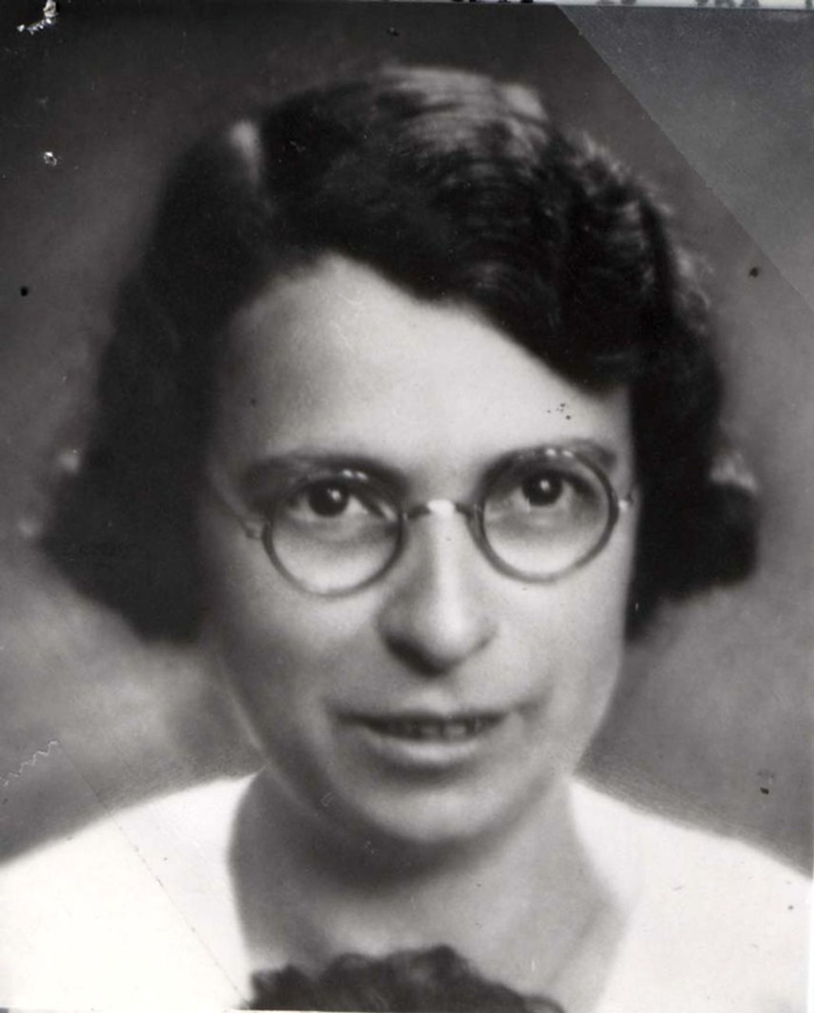 Black and white portrait of a woman wearing round glasses, looking directly at the camera.