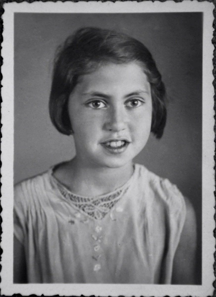 Vintage black and white portrait of a young girl with an earnest expression, wearing an embellished blouse.