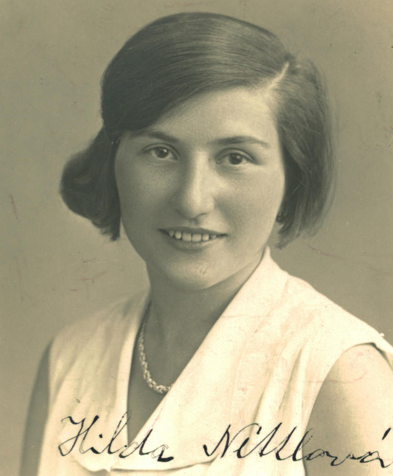 Vintage portrait of a woman, smiling, in a white dress with a necklace.