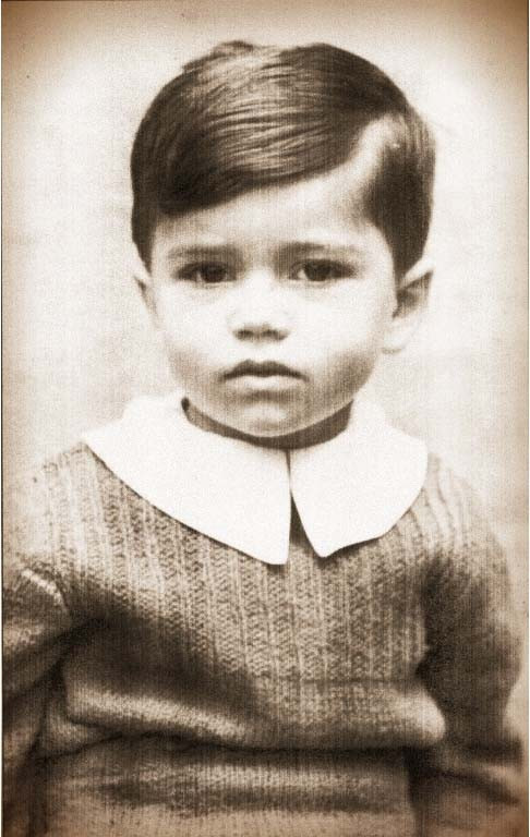 Vintage black and white photo of a young boy with neatly combed hair, wearing a sweater and collared shirt.