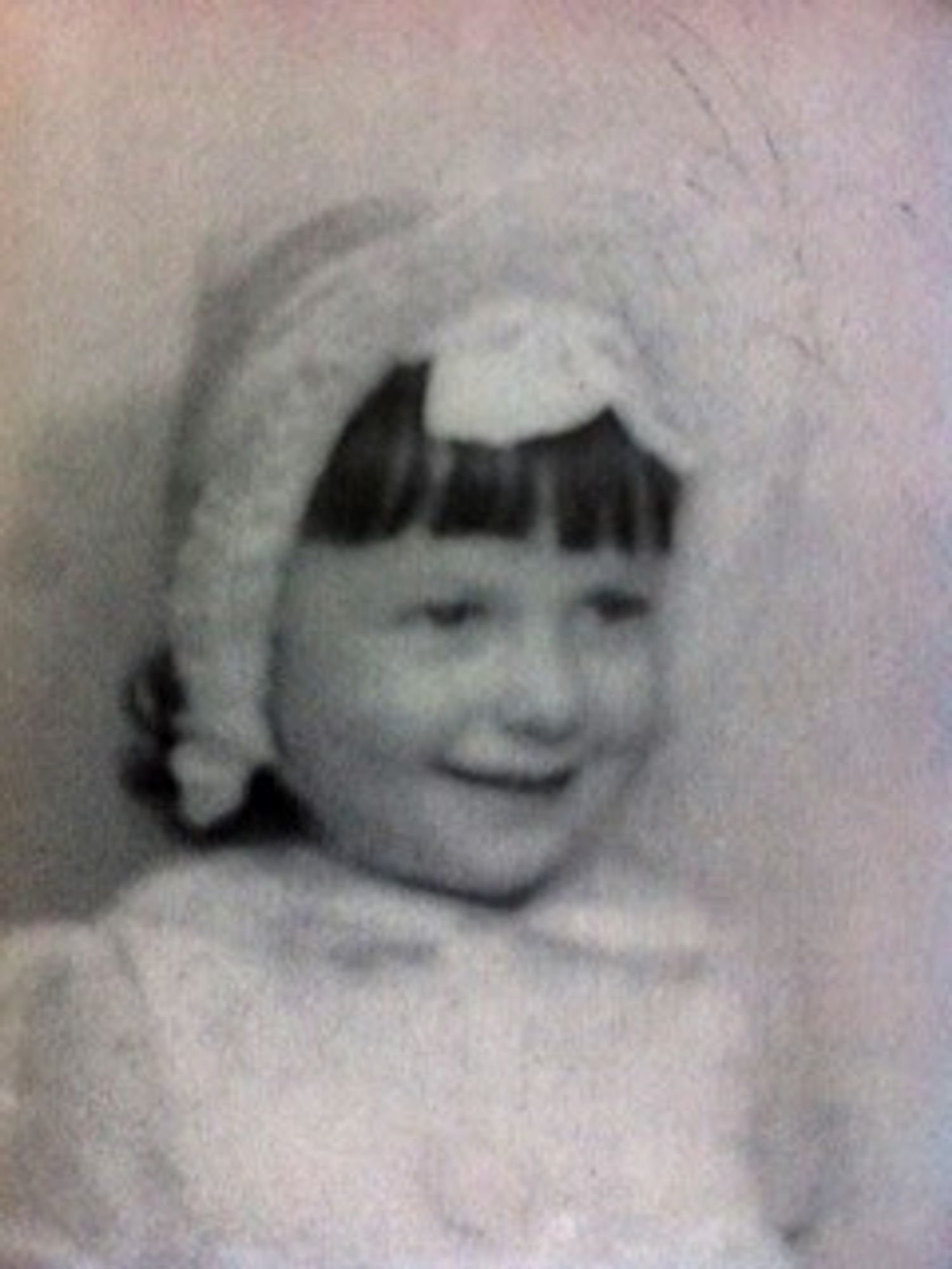 Vintage black and white photo of a smiling child wearing a bonnet.