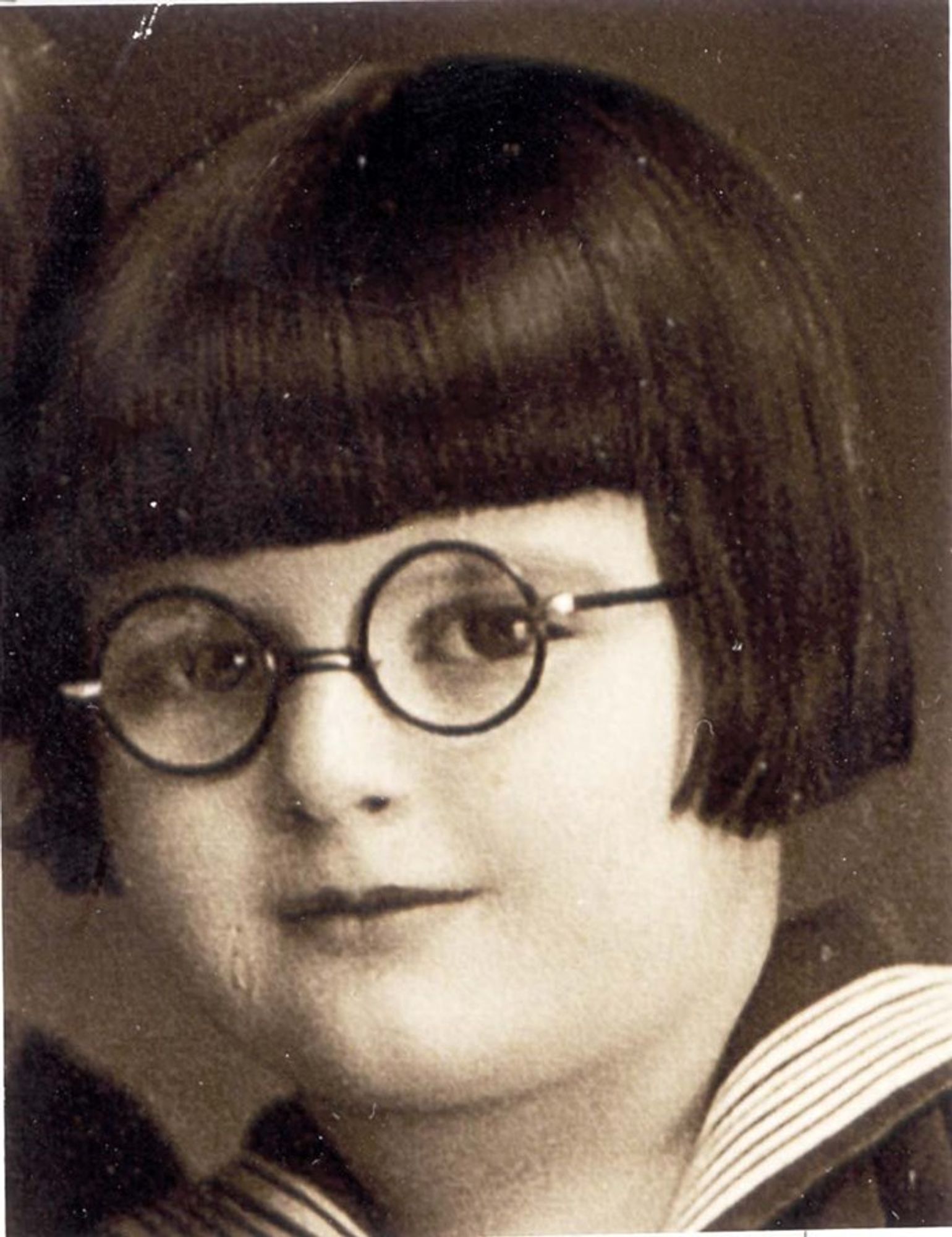 Vintage black and white portrait of a young girl with round glasses.
