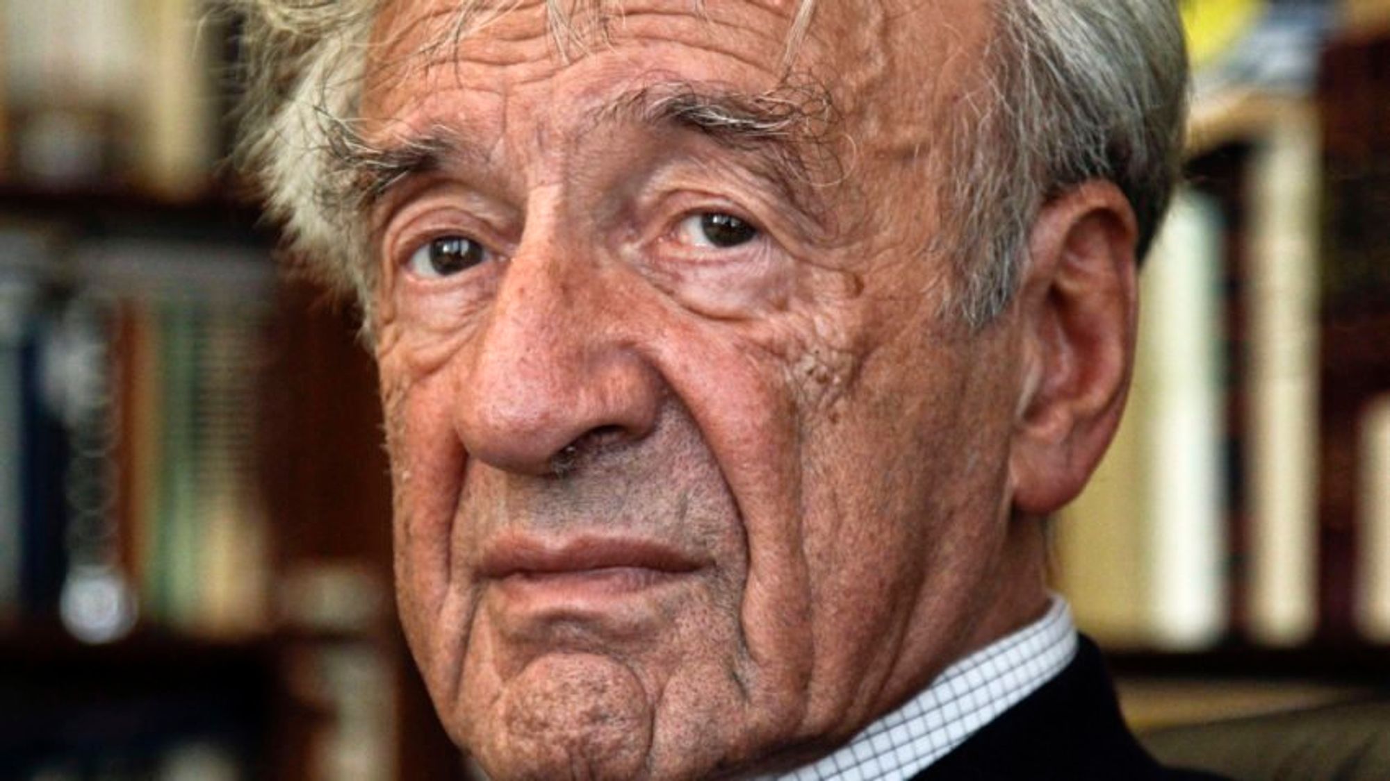 Close-up portrait of Elie Wiesel with a solemn expression, featuring detailed facial features and a blurred background.