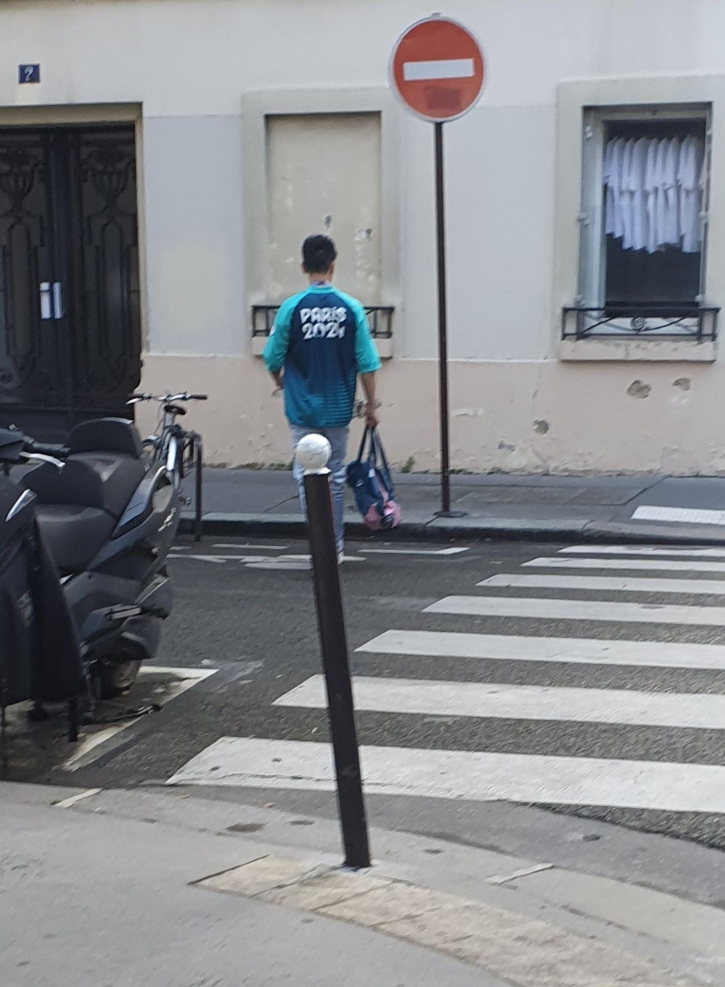 A volunteer of the Paris 2024 Olympics in his volunteer uniform in a nondescript side street of Paris