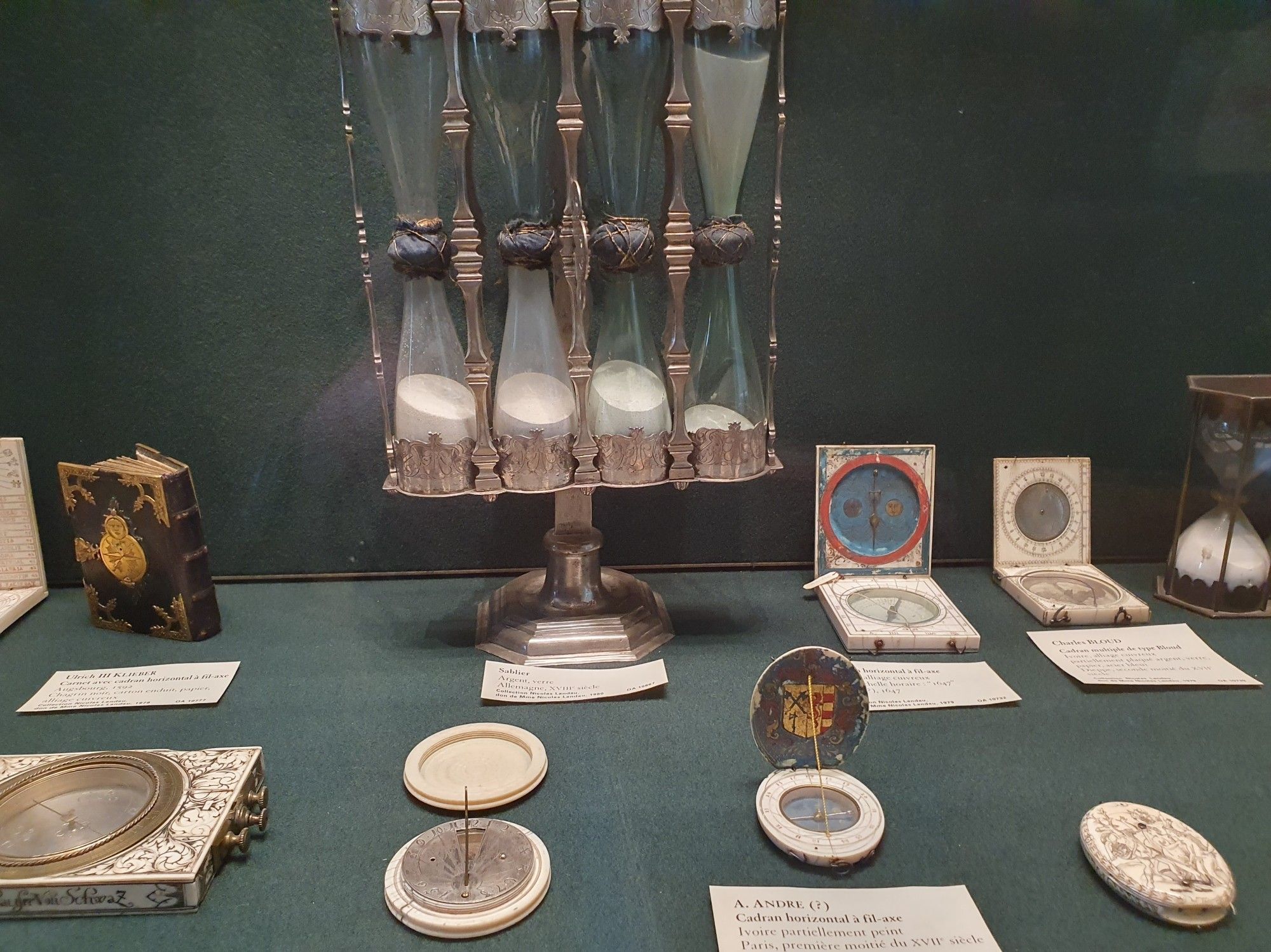 Museum display of portable sundials, a quadruble sandglass in the background