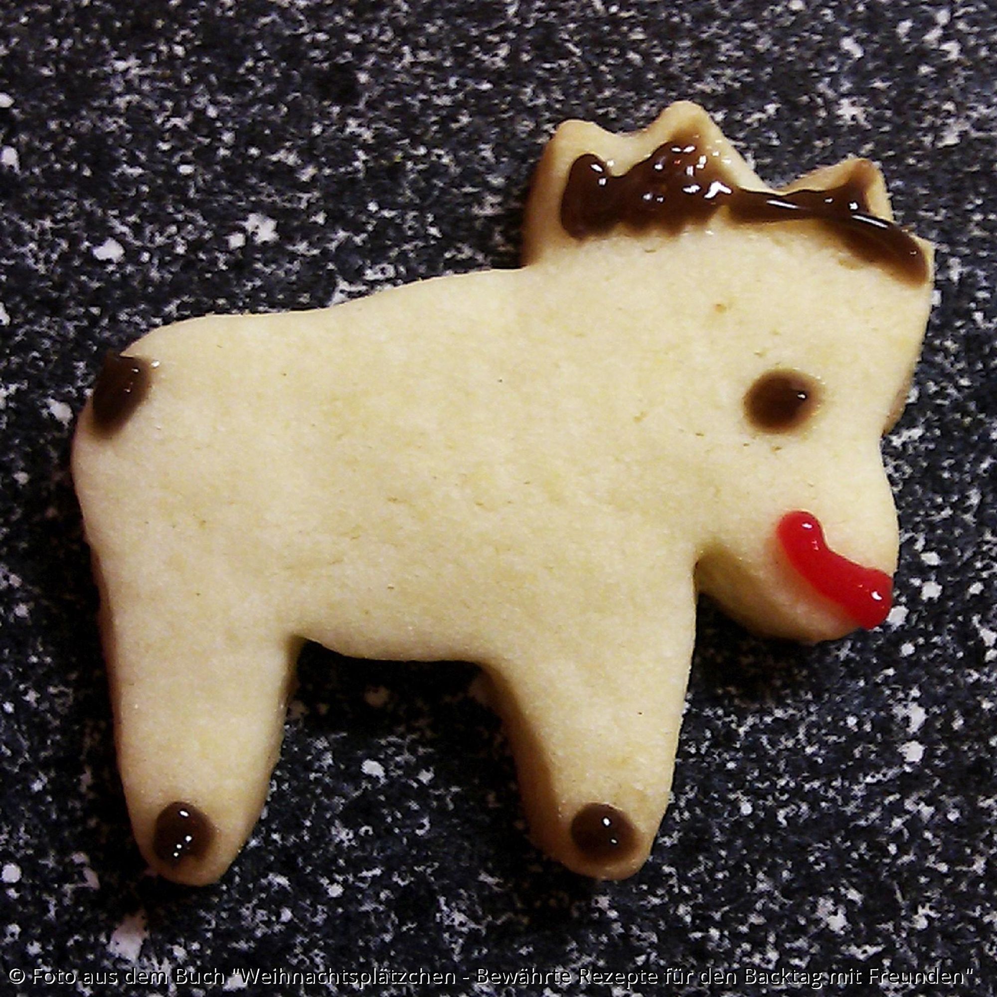 Ein Weihnachtsplätzchen in Elchform und mit Zuckerschrift aufgemalten Hufen, Schwanz, Geweih, Augen und Maul.