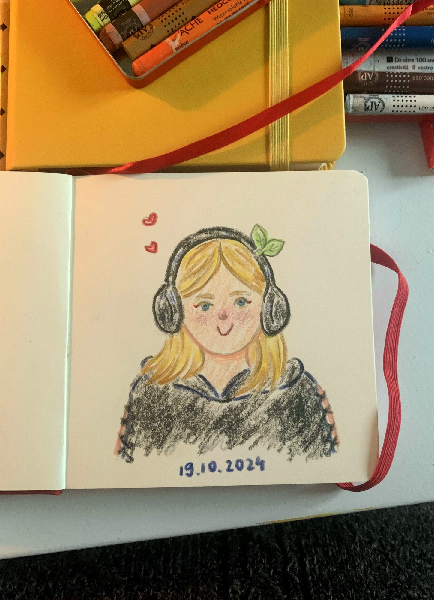 Sketchbook drawing of a girl (my girlfriend) wearing headphones; she is smiling, there are hearts around her head and green sprouts on the right side of the  headphones ; crayon drawing 