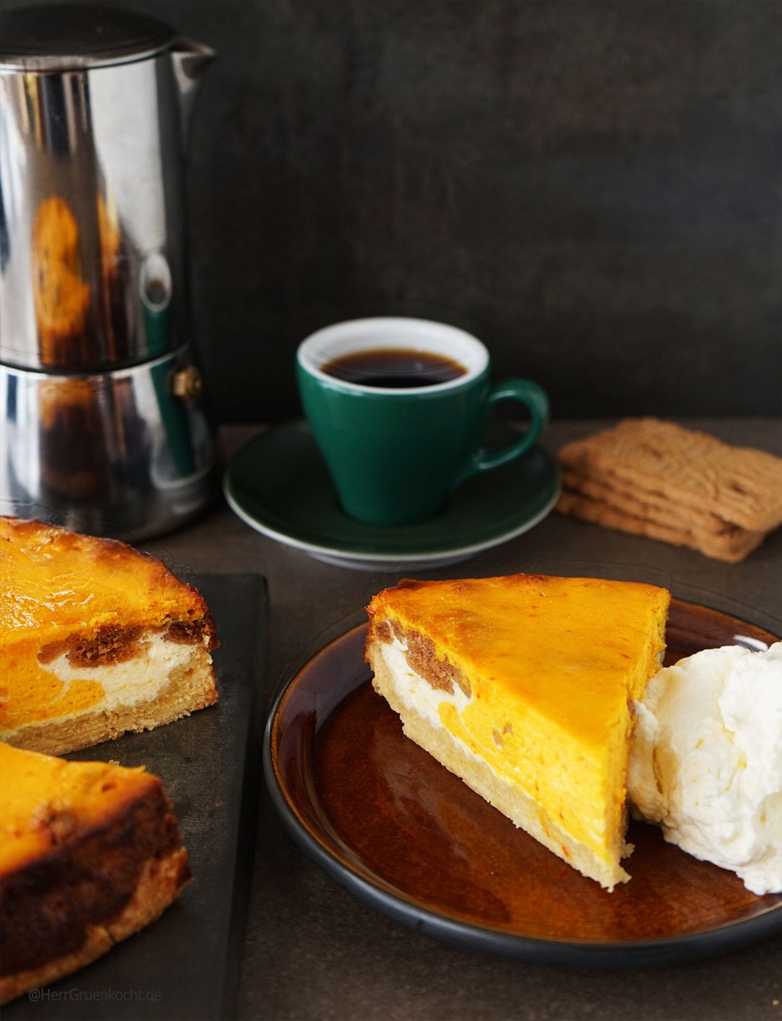 Ein brauner runder Kuchenteller mit einer Käse-Kürbistarte mit Spekulatiusbröseln und einem krossen Dinkel-Mürbeiteig