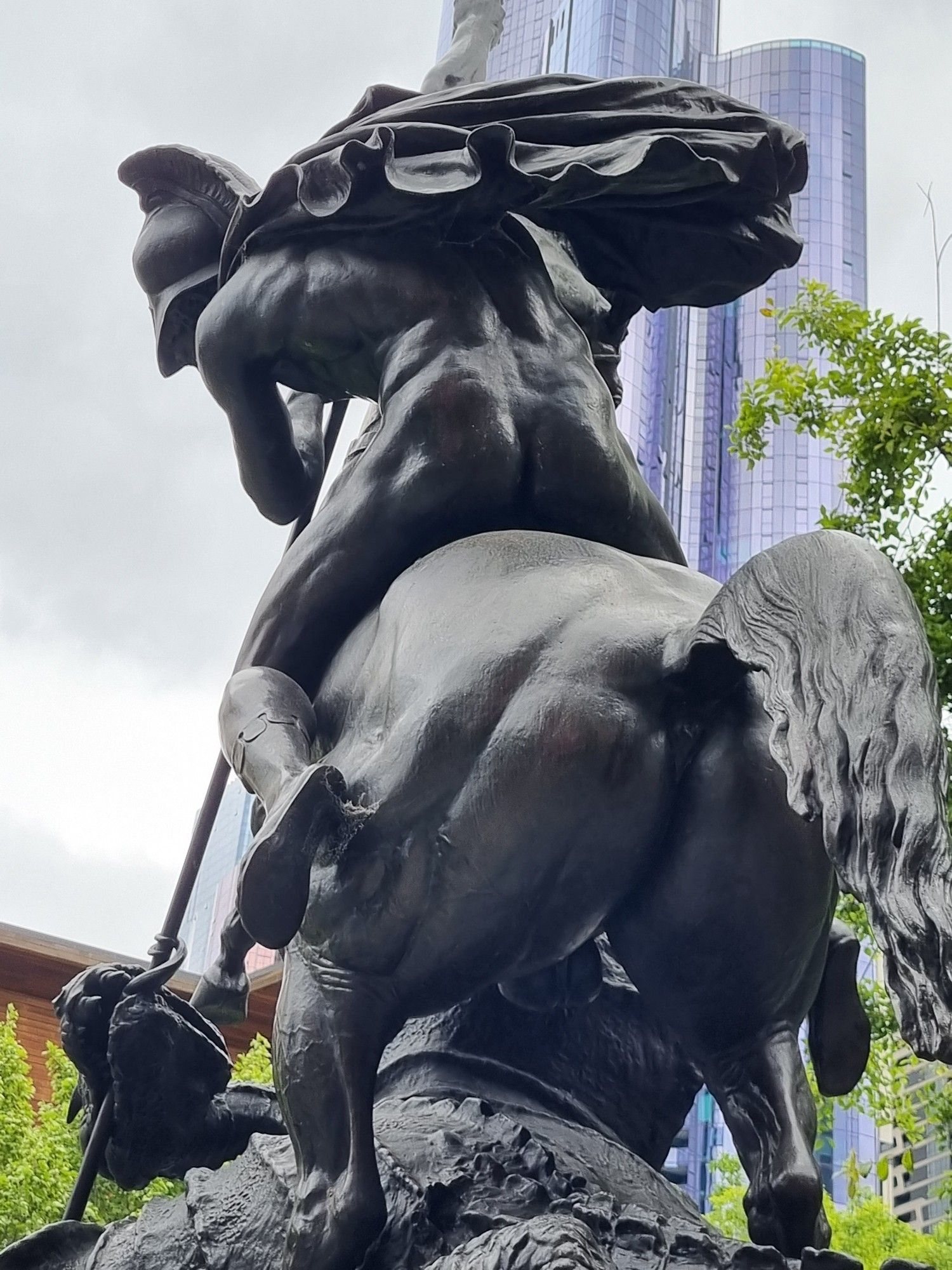 A photo of the rear of a statue of St George and the Dragon. Cast in bronze, the horses arse and St George's fine arse are visible.