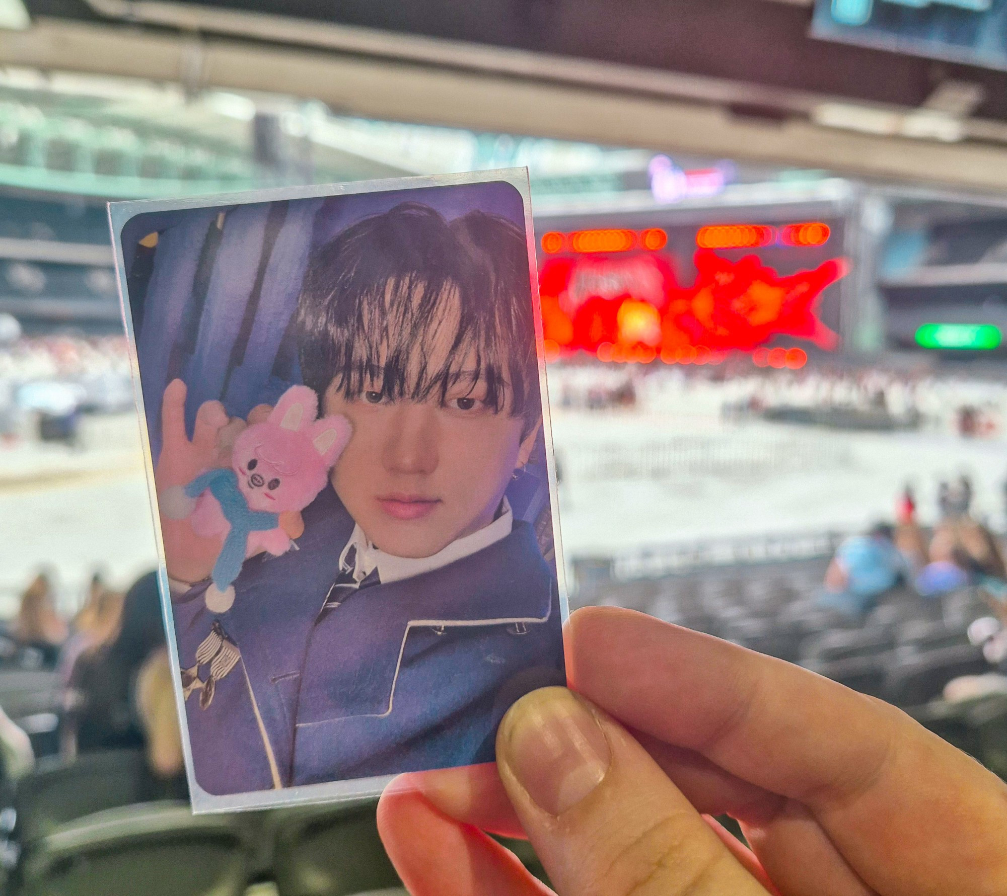 Tayla is hold up a photocard of changbin and dwaekki in front of the stray kids concert.