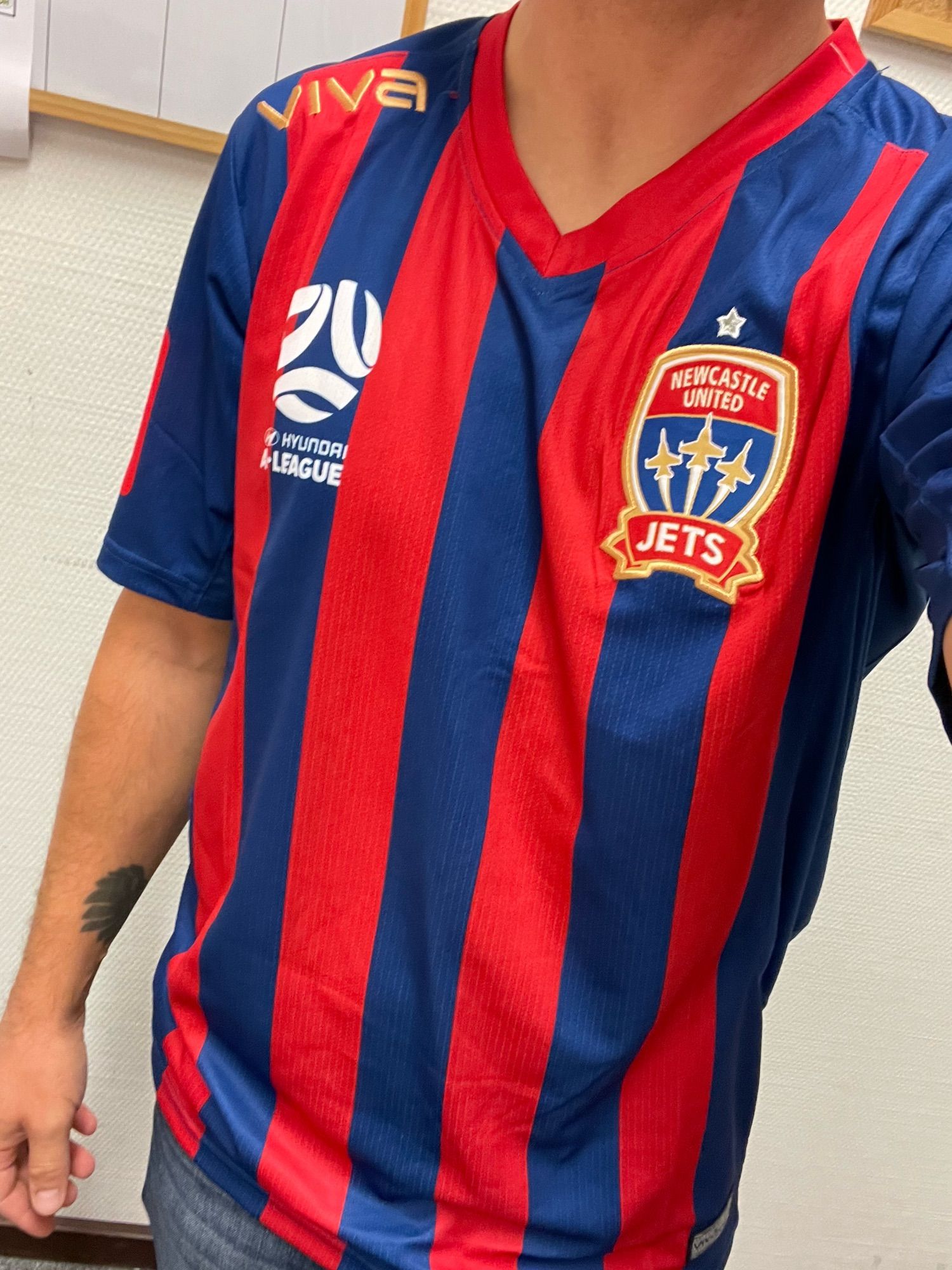 Bild von mir in einem rot-blauen Trikot des australischen Fußballvereins Newcastle United Jets.