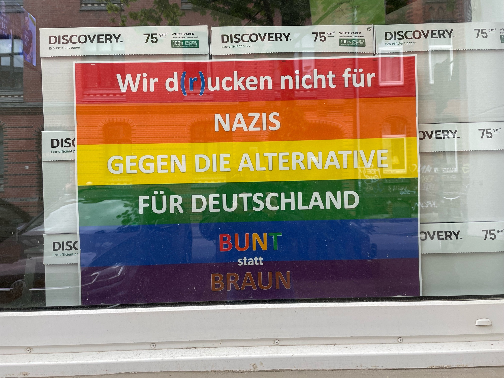 Regenbogen Plakat mit der Aufschrift:

Wir d(rucken nicht für
NAZIS
GEGEN DIE ALTERNATIVE FÜR DEUTSCHLAND
BUNT
statt
BRAUN