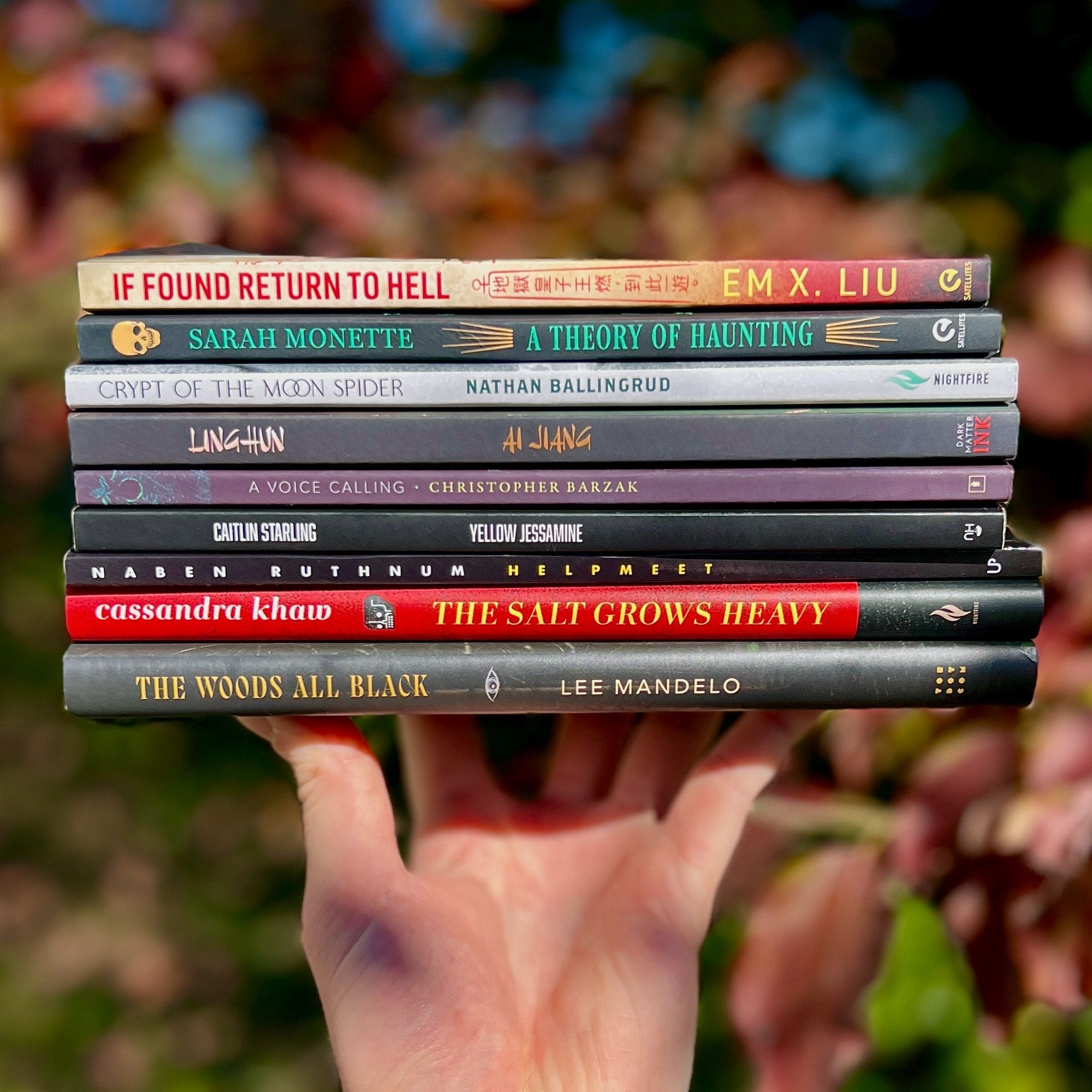 [Image desc: A stack of books (from top to bottom): IF FOUND, RETURN TO HELL by Em X. Liu, A THEORY OF HAUNTING by Sarah Monette, CRYPT OF THE MOON SPIDER by Nathan Ballingrud, LINGHUN by Ai Jiang, A VOICE CALLING by Christopher Barzak, YELLOW JESSAMINE by Caitlin Starling, HELPMEET by Naben Ruthnum, THE SALT GROWS HEAVY by Cassandra Khaw, THE WOODS ALL BLACK by Lee Mandelo.]