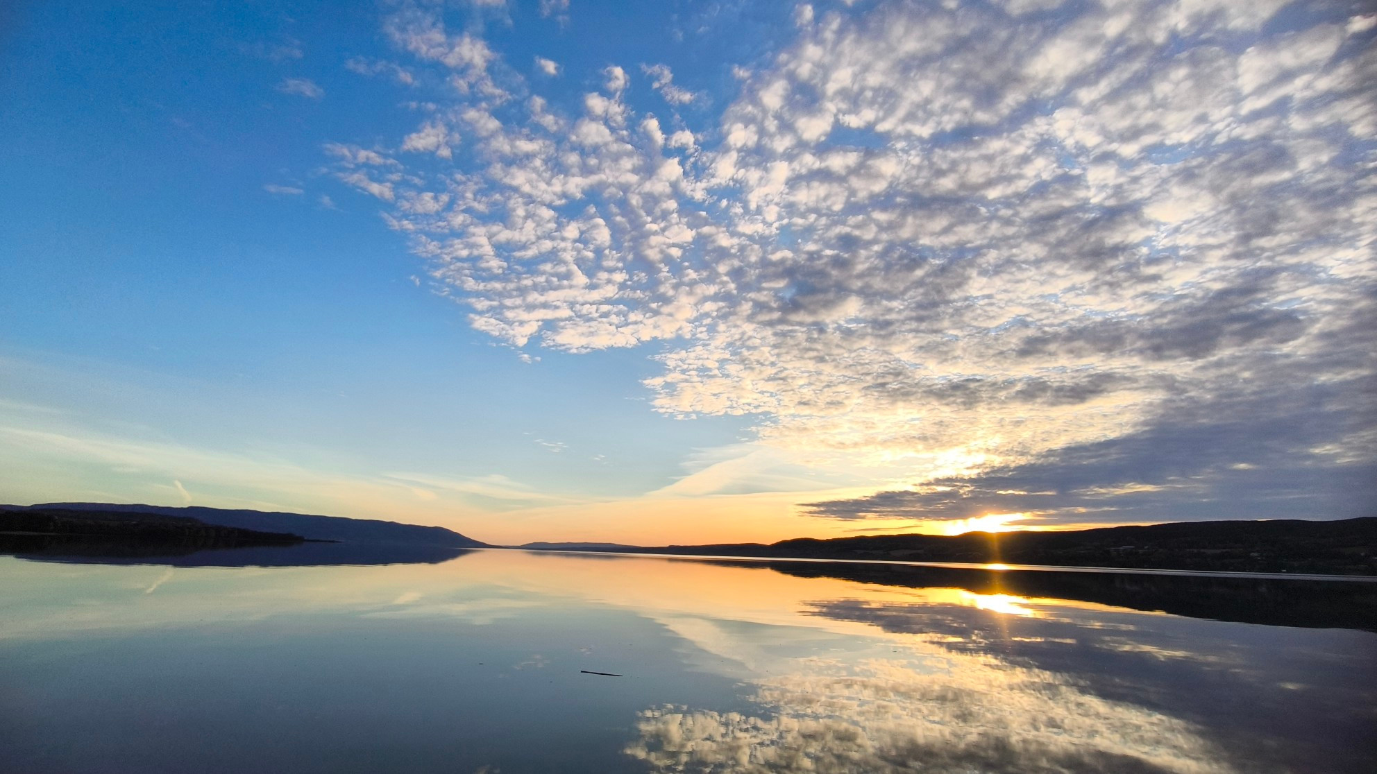 Abendsonne mit Wolken an einem stillen See in Norwegen