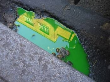 a puddle of bright green liquid by the curb