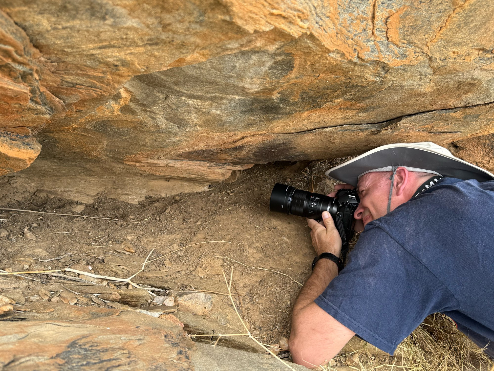 person photographing assassin fly under rock overhang