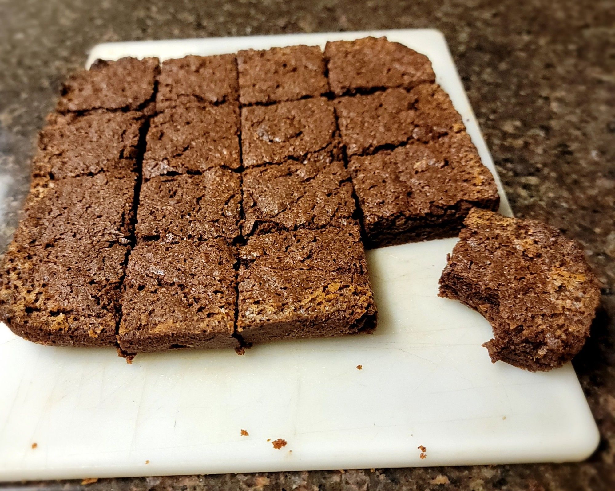 Picture is of brownies on a cutting board. There are 16 of them. The one in the bottom right corner has a bite taken out of it.