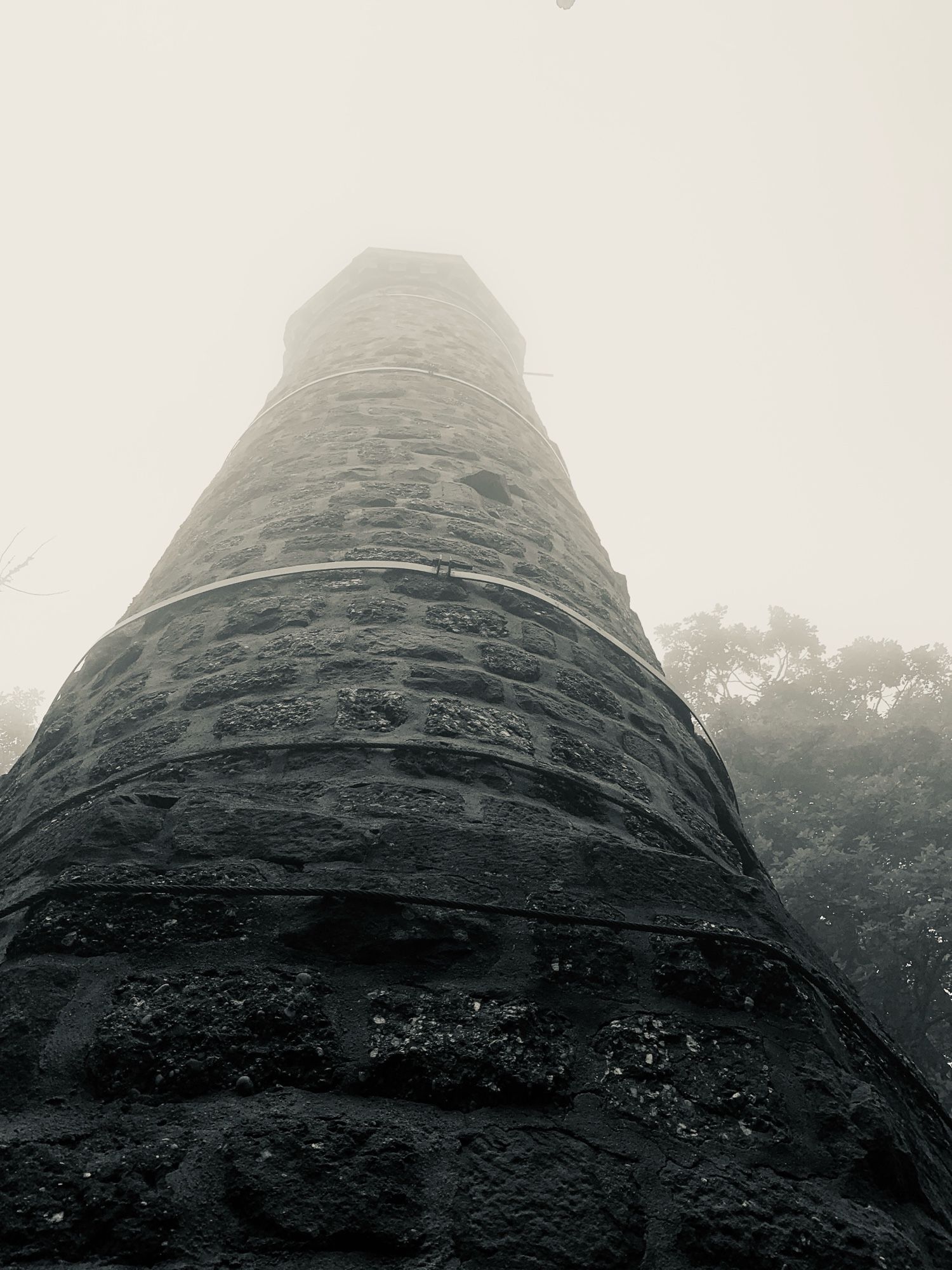 Aus Feldsteinen gemauerter Aussichtsturm im Nebel.