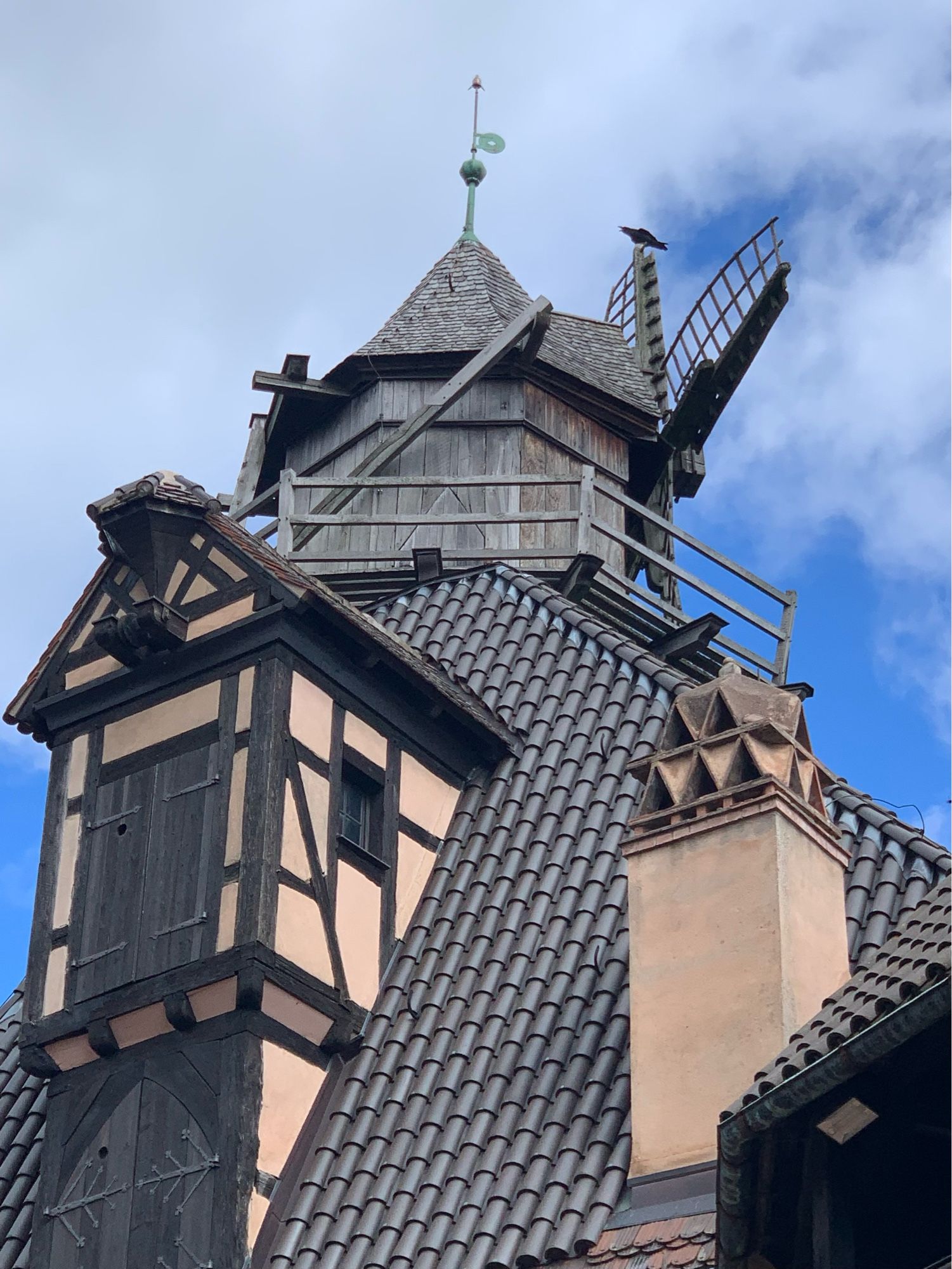 Ein Dach mit Fachwerkgaube und Holzturm mit Windmühlenflügeln