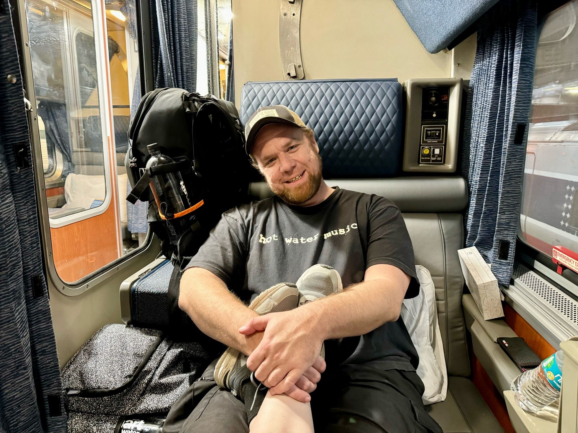 Guy sitting on one side of a two room compartment on Amtrak.