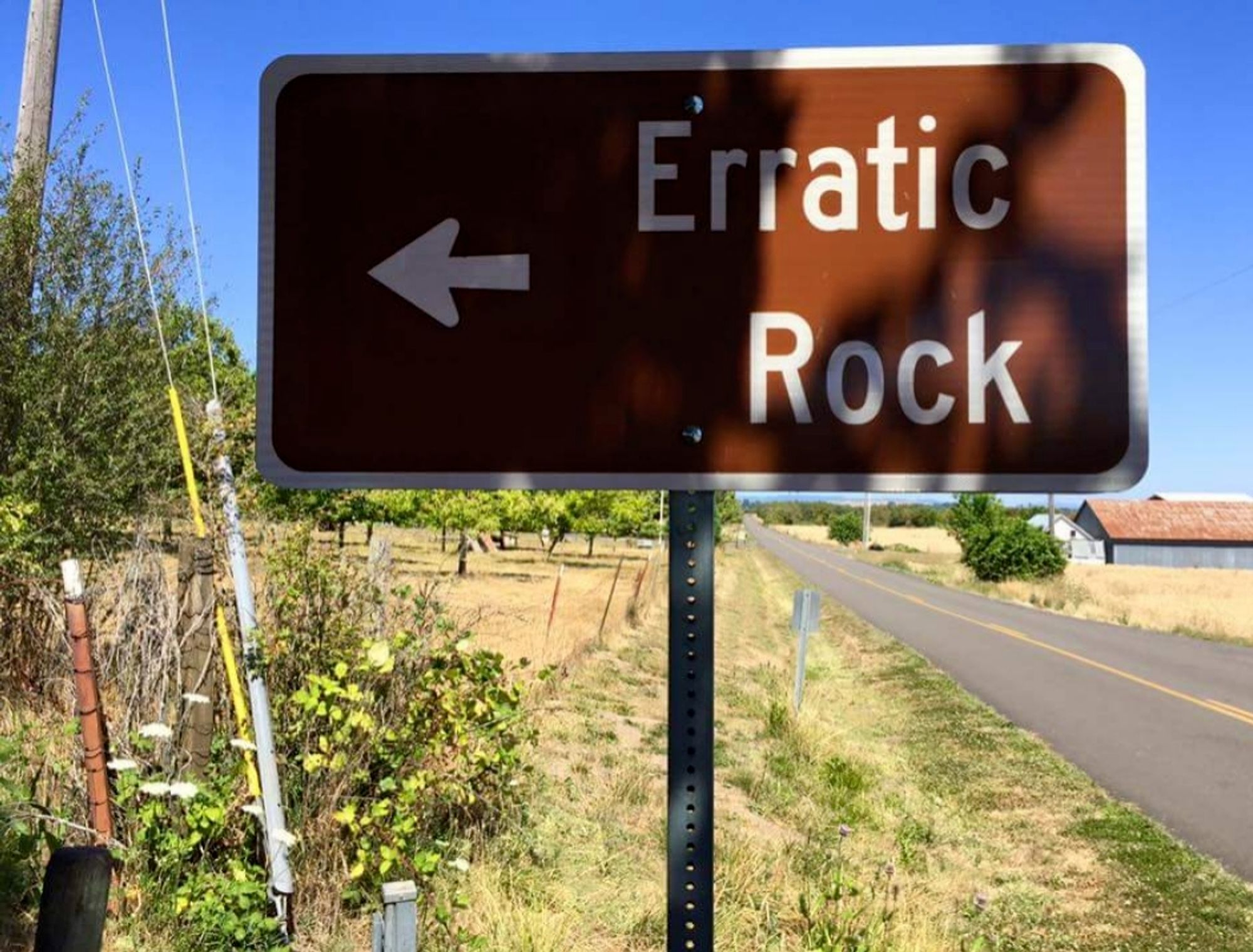 Brown roadsign showing exit for "Erratic Rock" off to the left. The landscape is flat and there are vineyards and farm buildings in the distance

(Photo from a friend. I know where this was taken, no need to @ me)