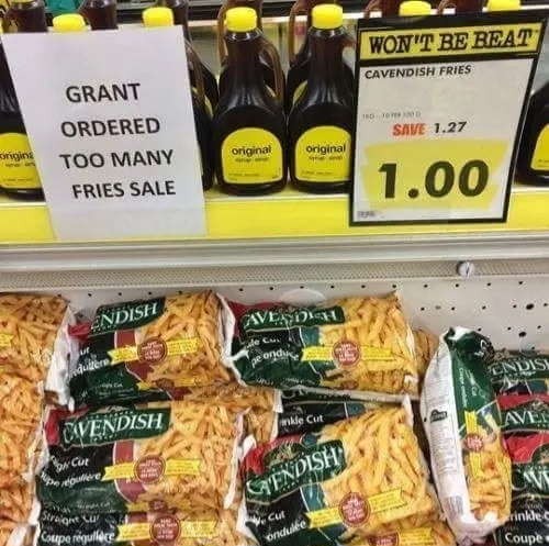 Supermarket fridge packed with Cavendish Crinkle Cut Chips. A special savings sign to the right above the packets says:
"Cavendish Fries
Save 1.27
1.00"

To the left of that is another, printed on plain paper:
"Grant
Ordered
Too Many
Fries Sale"