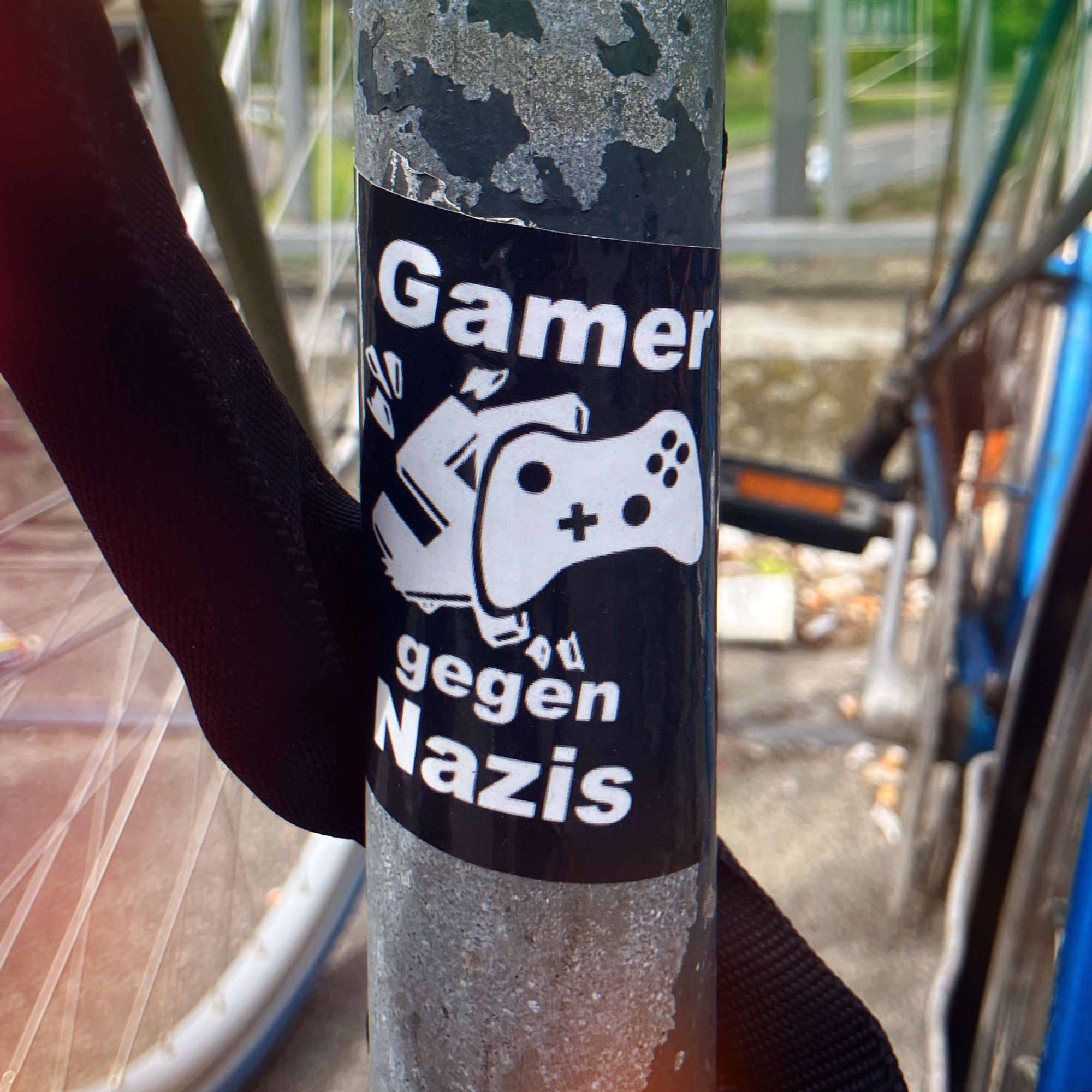 sticker an einem fahrradständer: ein game-controller der ein hakenkreuz zerschlägt, dazu steht: Gamer gegen Nazis